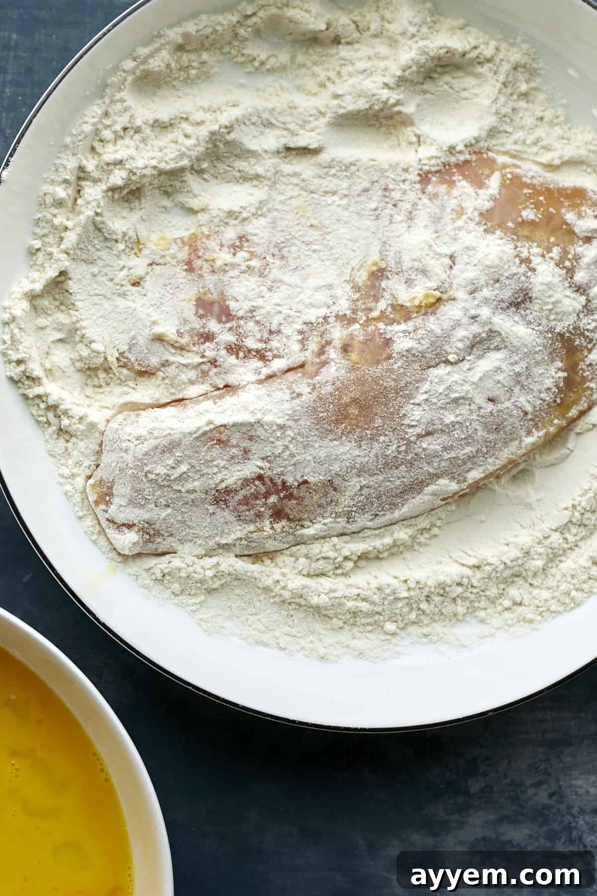 Tilapia fillet being dredged in flour, as part of the breading process.