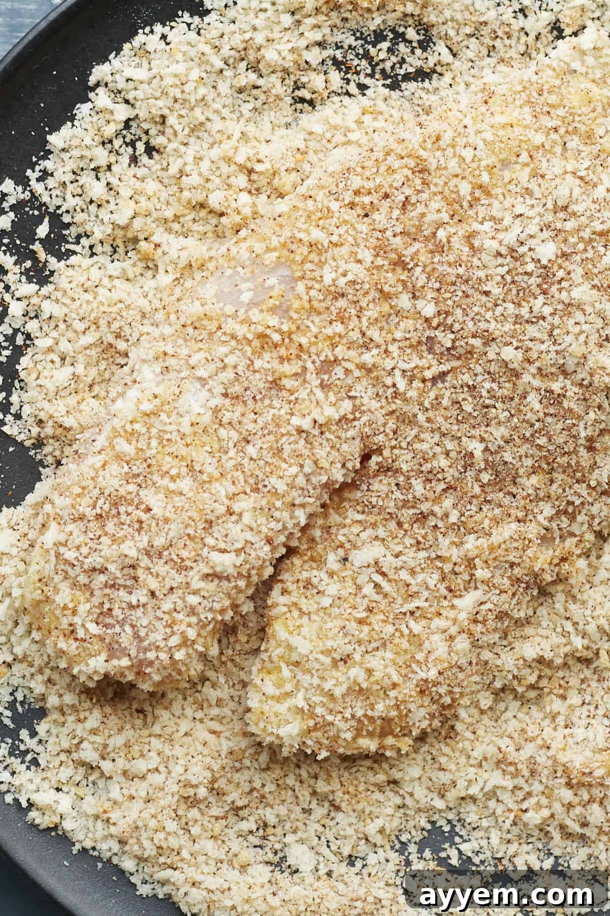 An uncooked tilapia fillet, fully breaded and ready for air frying.