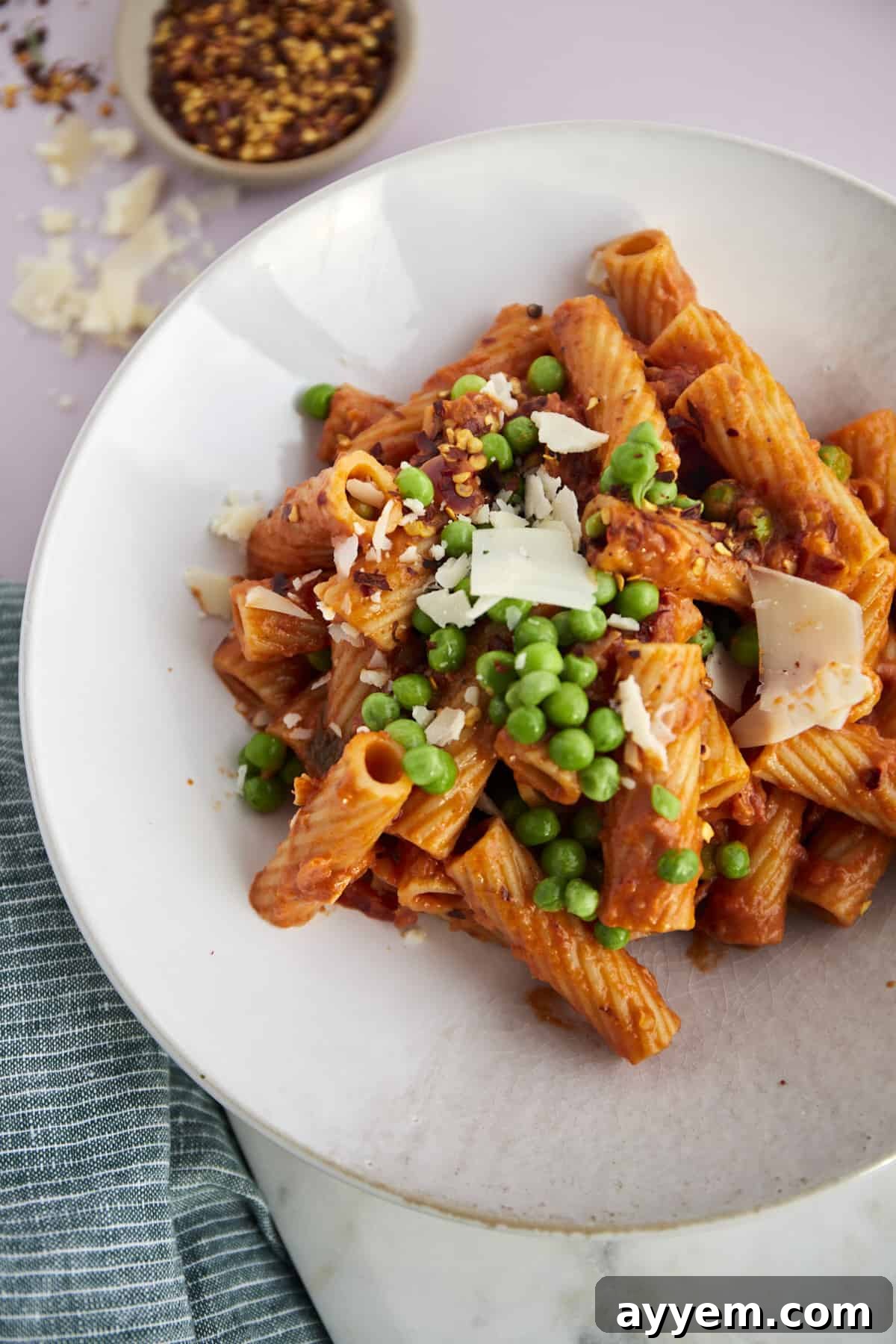 Fiery Rigatoni Bake 4 a plate full of spicy baked rigatoni with peas topped with shaved cheese