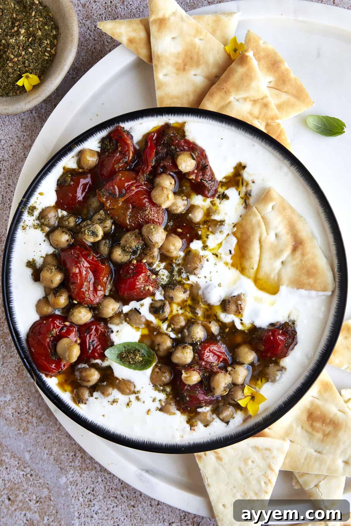 Delicious Creamy Whipped Feta Dip with Roasted Tomatoes and Chickpeas, garnished with fresh herbs and olive oil, served with pita bread.