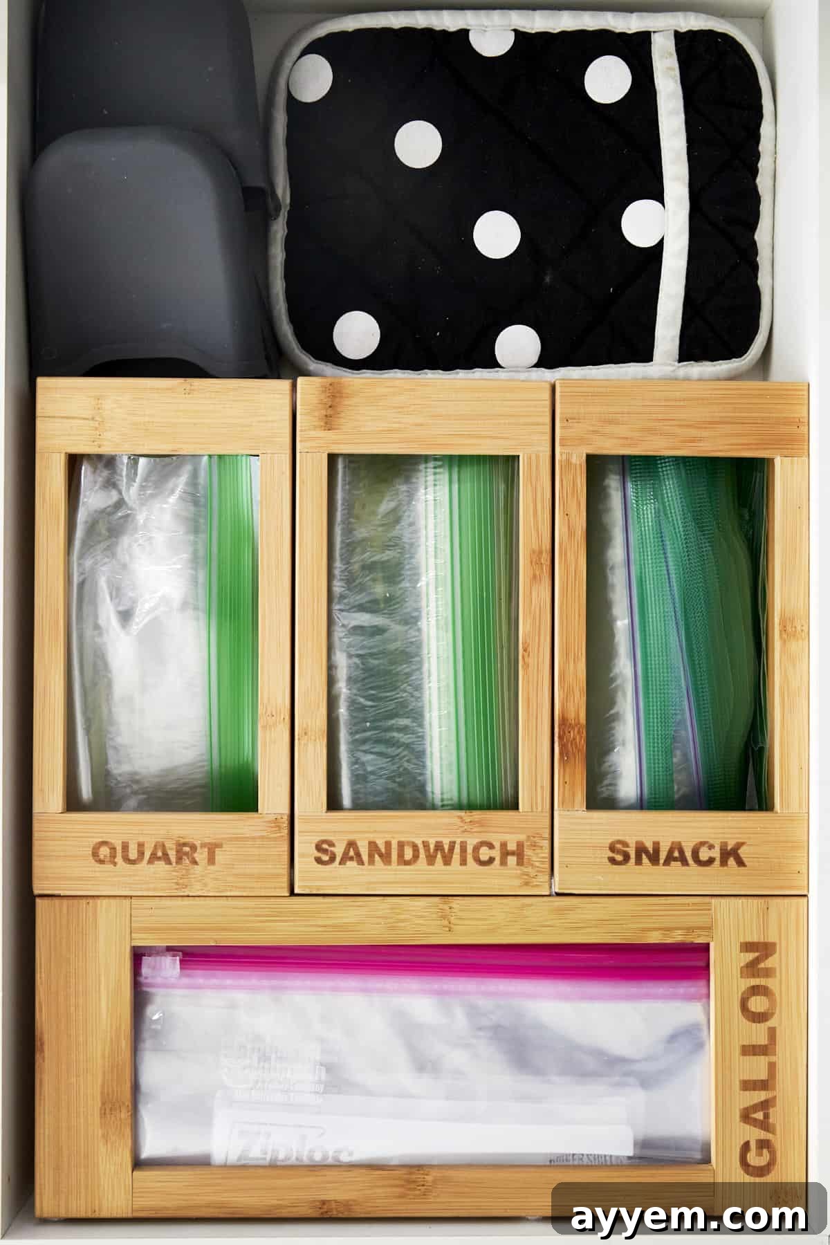 A perfectly organized kitchen drawer with Ziploc bag organizers, showcasing neat compartments for different bag sizes like gallon, quart, sandwich, and snack.