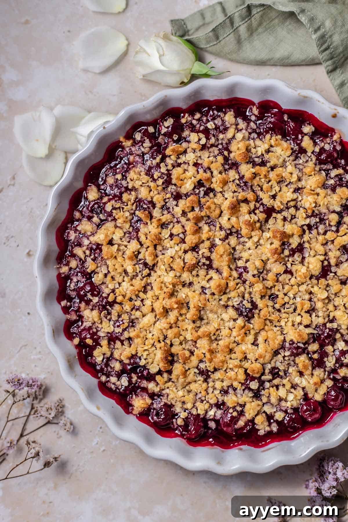 An overhead view of a freshly baked cherry crisp, showing the vibrant red cherry filling bubbling through the golden-brown, crunchy oat topping.