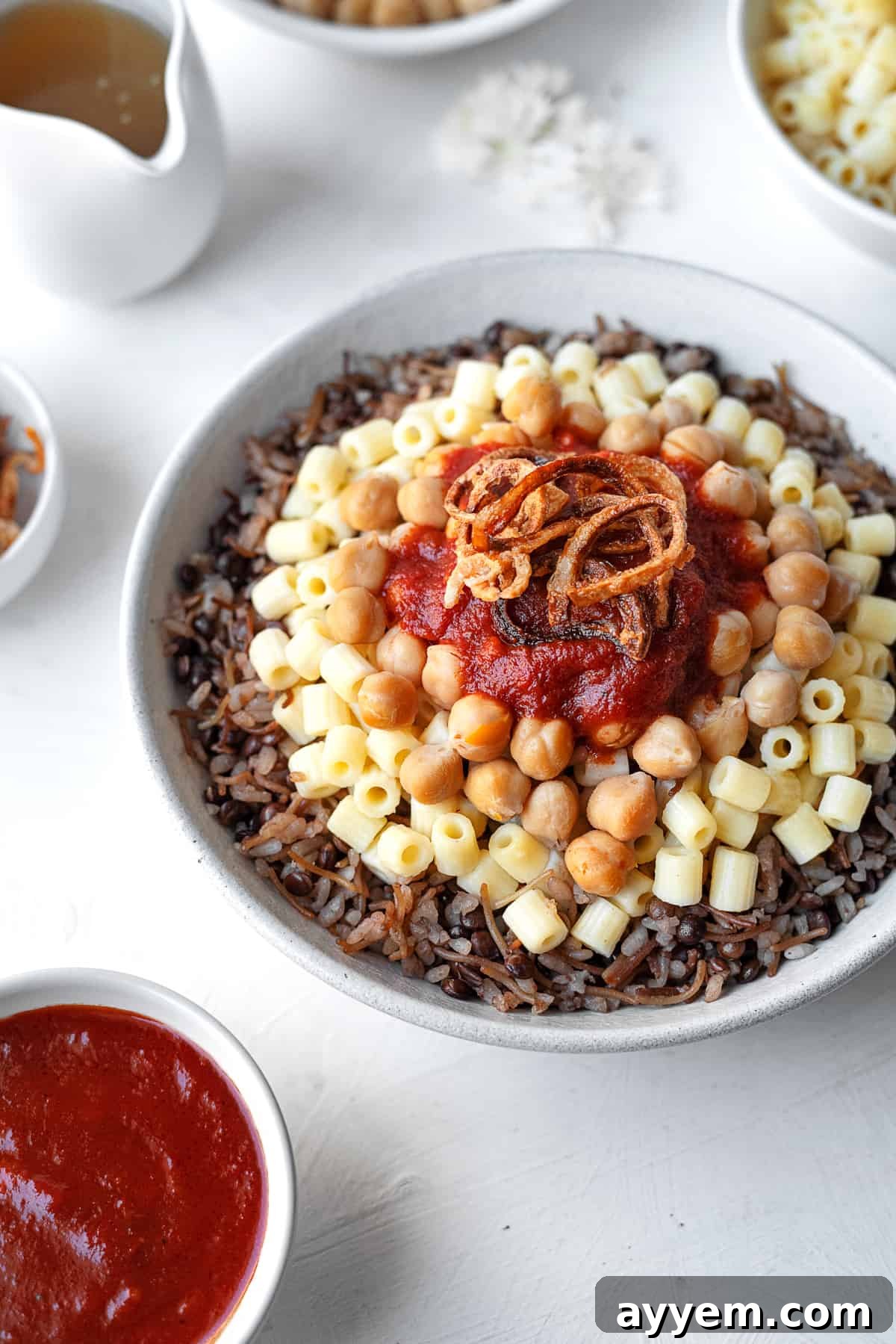 close up view bowl of koshari with the fixings on top and the sides