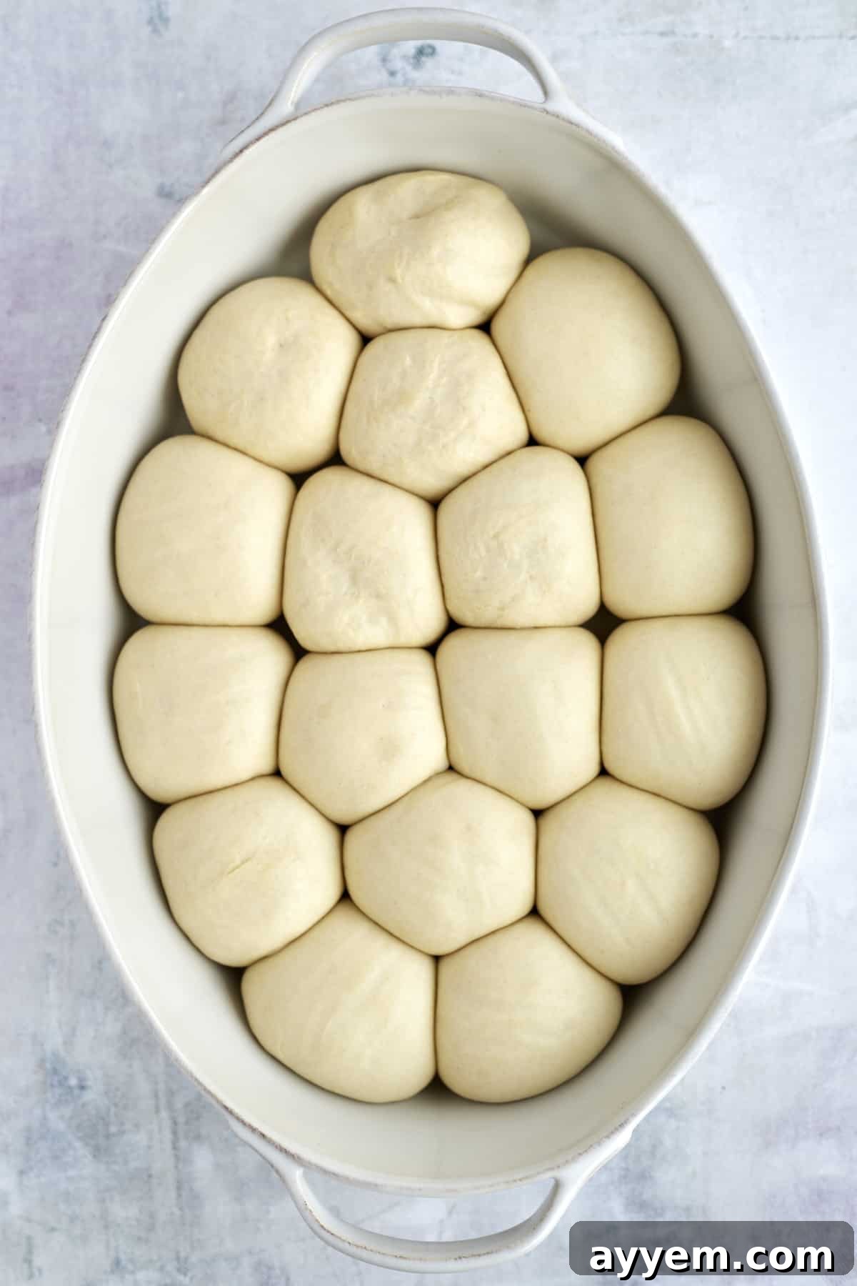 risen unbaked bread rolls in a baking dish