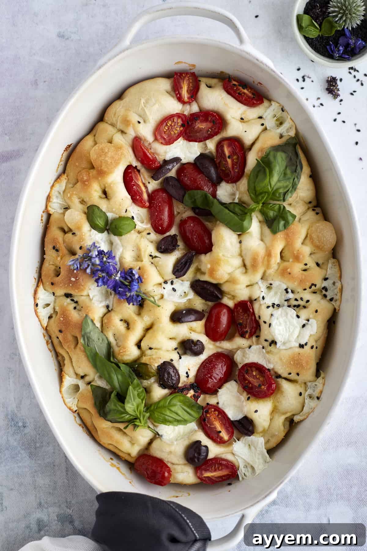 baked no knead focaccia bread with tomatoes, olives, fresh herbs, mozzarella, and herbs