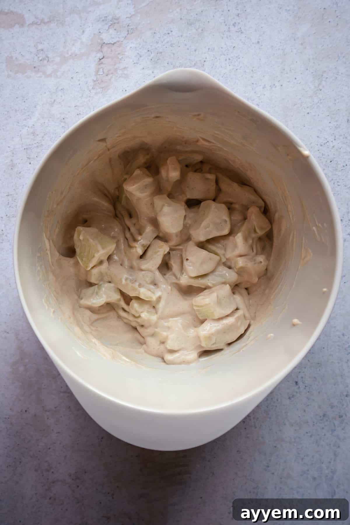 The chopped apples fully incorporated into the cream cheese and cinnamon mixture, creating a rich, textured filling.