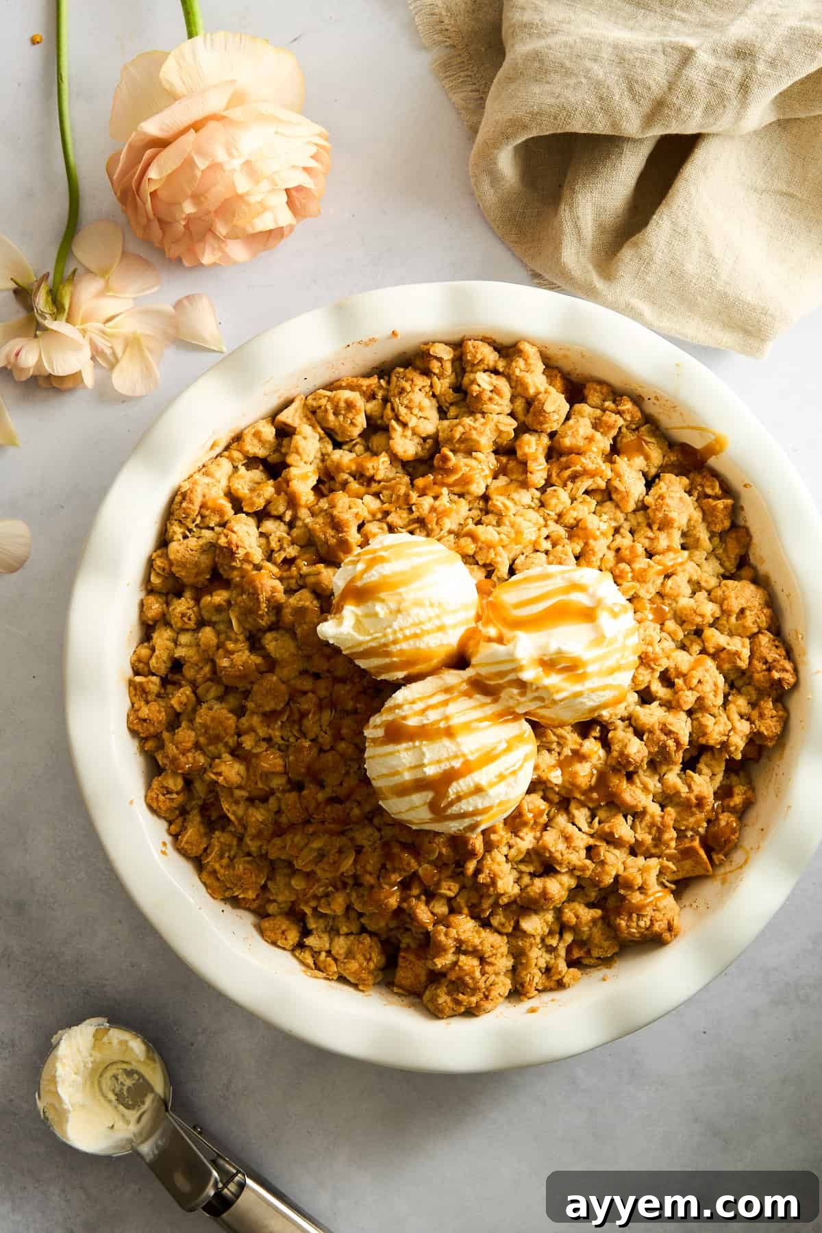 Apple crisp topped with vanilla ice cream and caramel sauce, beautifully plated and ready to be enjoyed.