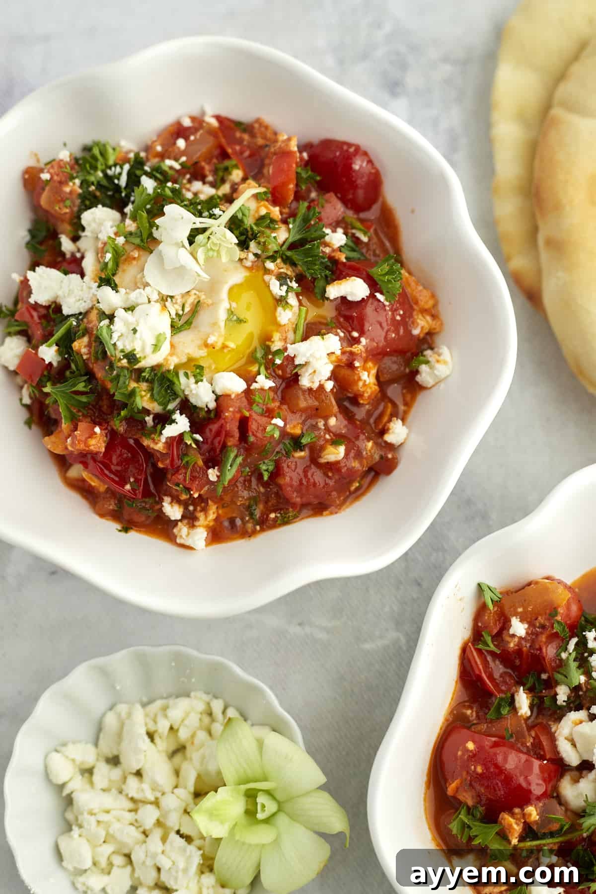 Feta Shakshuka Made Easy 11 Two white bowls brimming with easy shakshuka with feta, garnished with fresh herbs, ready for a delicious meal.