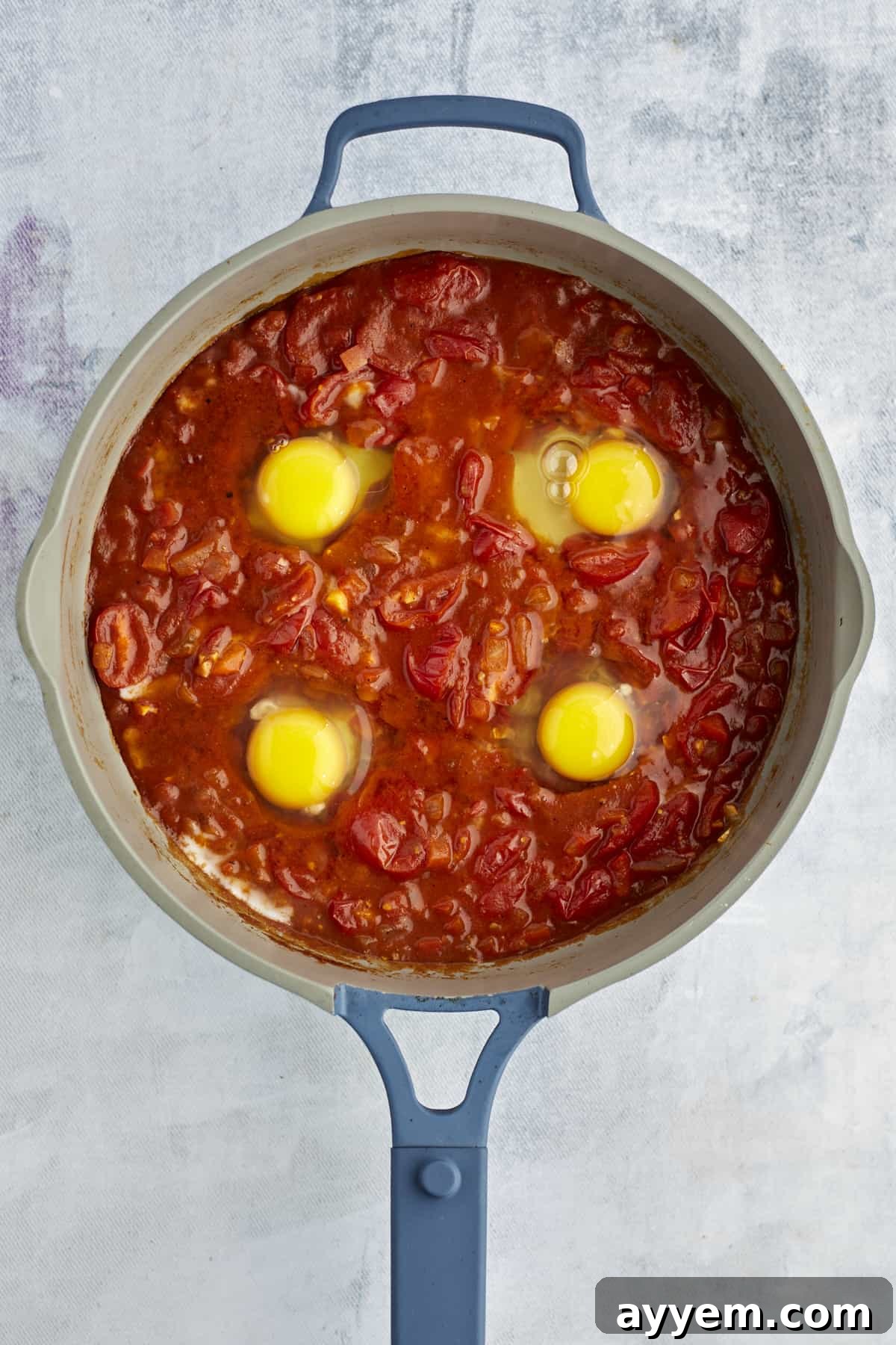 Feta Shakshuka Made Easy 8 Four perfectly cracked eggs nestled into the rich, simmering shakshuka sauce in a large pot, ready to poach.