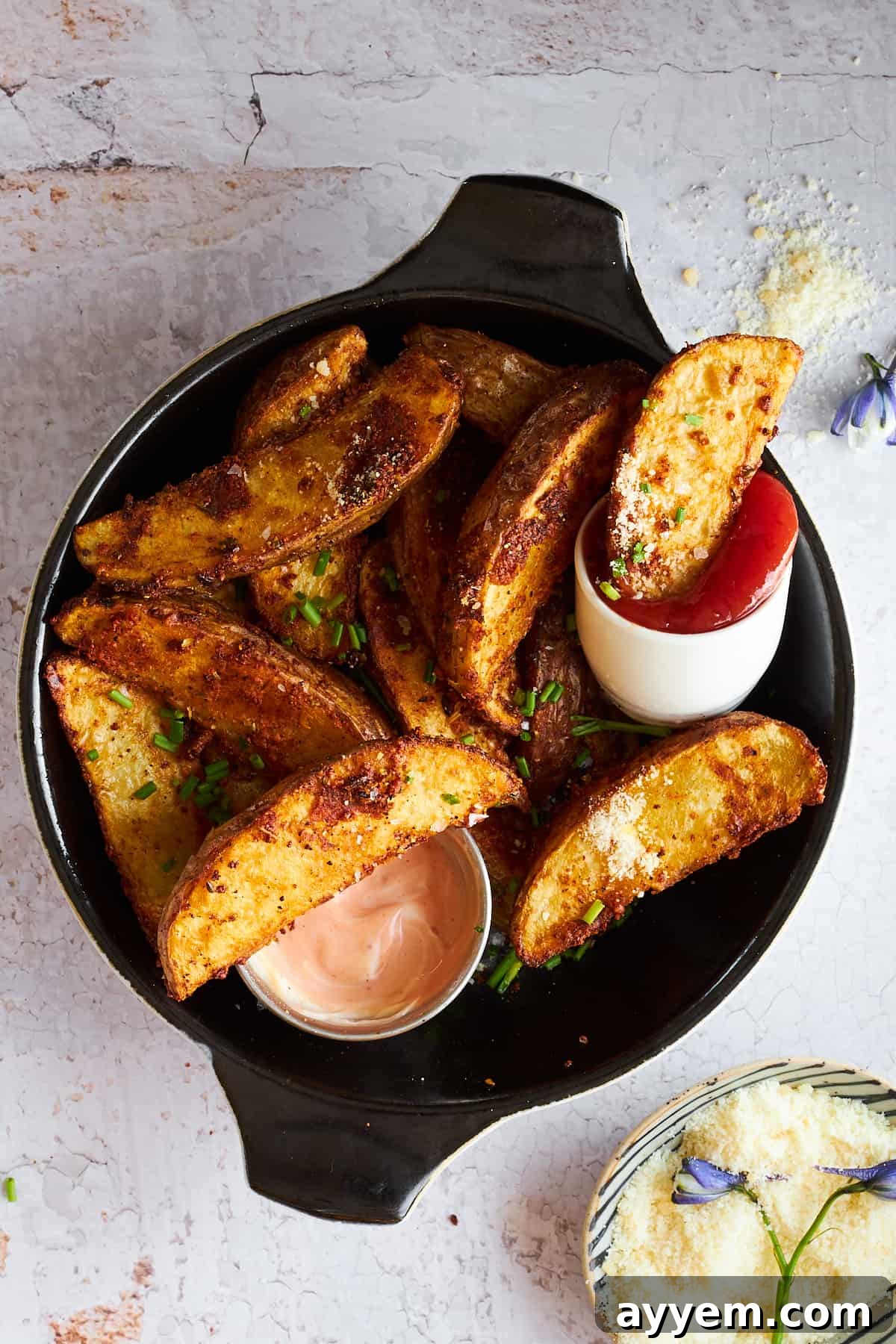 A plate of golden-brown garlic Parmesan potato wedges with various dipping sauces.