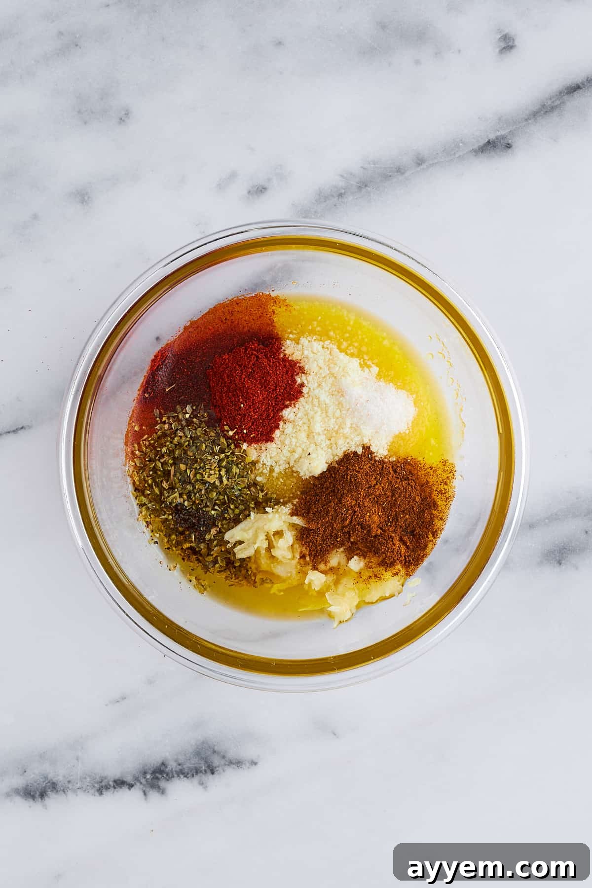 A bowl filled with a vibrant mix of garlic parmesan potato wedge seasonings, ready to be combined.