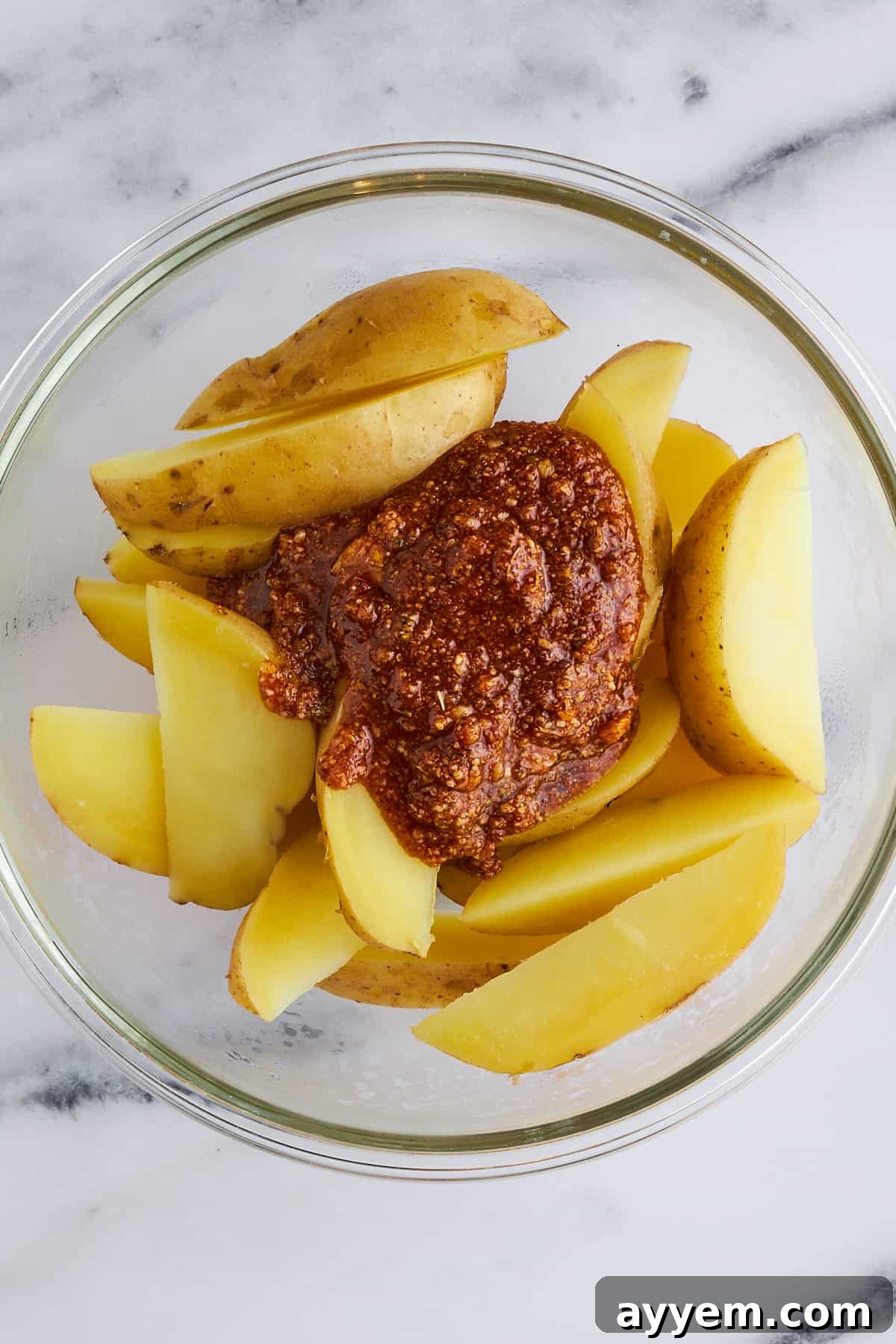 Potato wedges in a bowl, generously coated with the savory seasoning rub.
