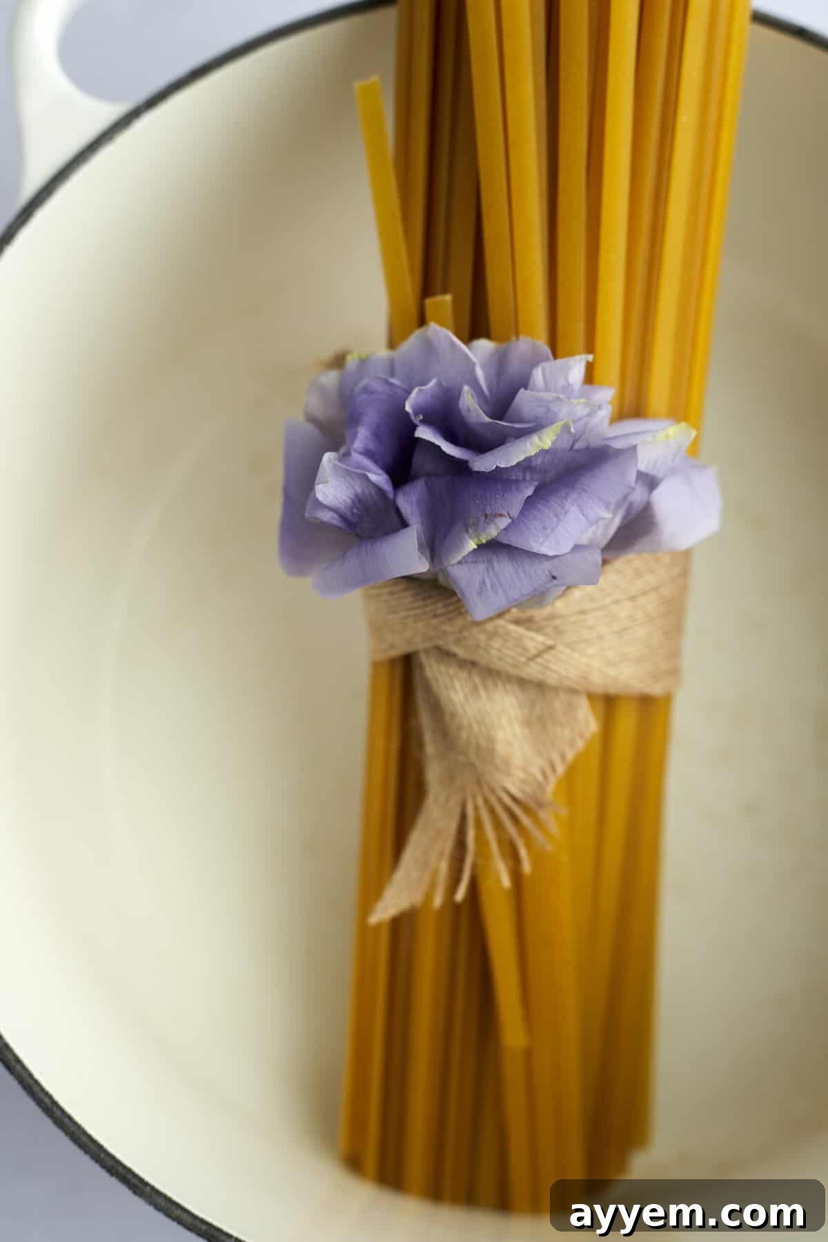 A bundle of dry fettuccine noodles being placed into a large cooking pot.