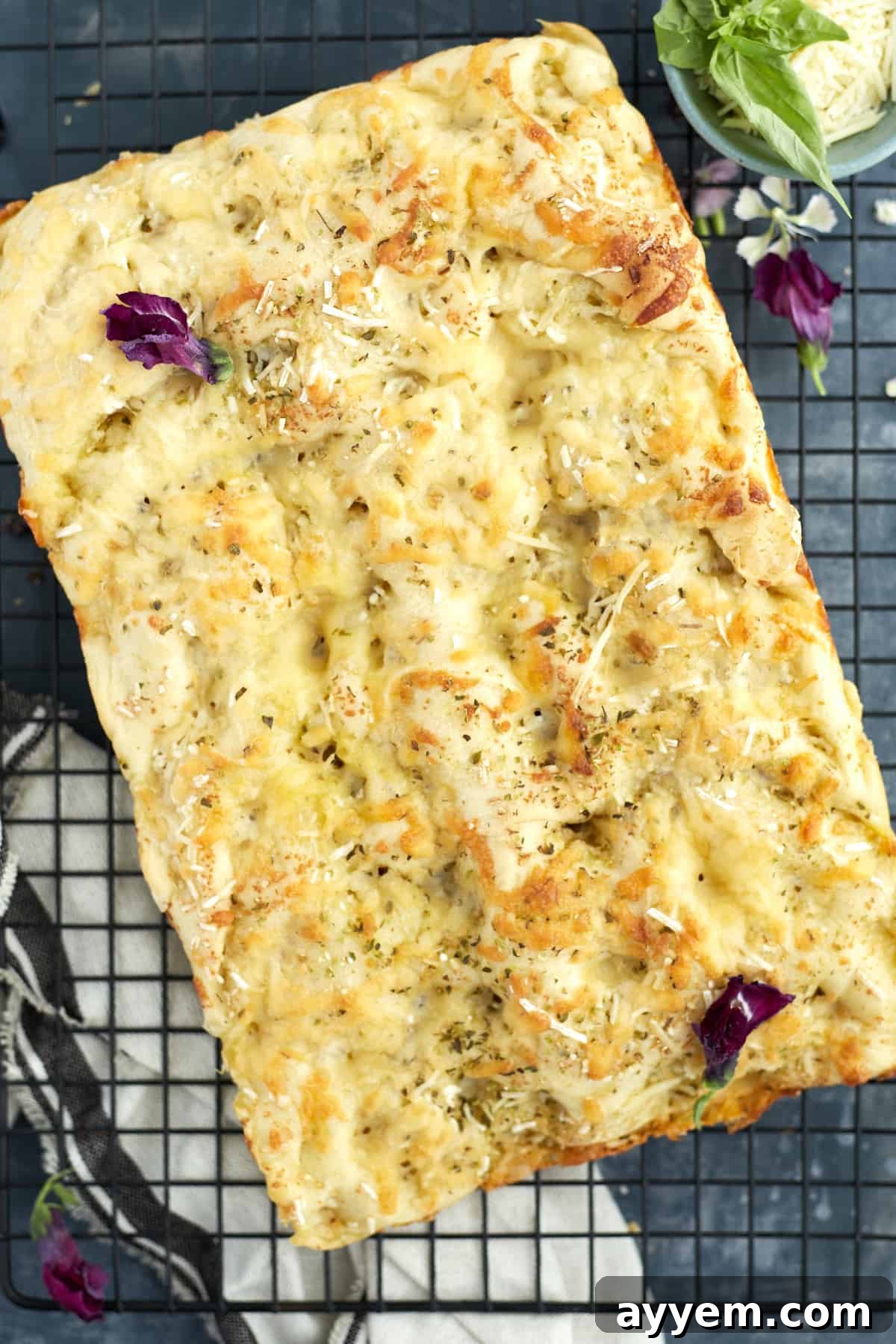 Freshly baked focaccia bread garnished with basil and edible flowers.