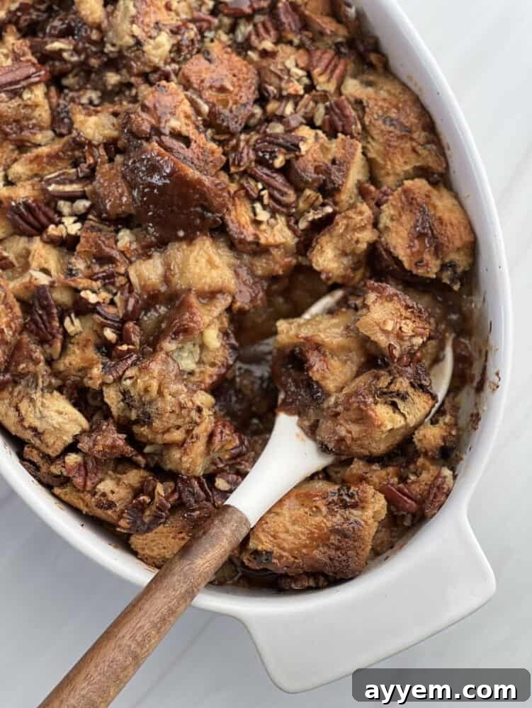 a baking dish of panettone bread pudding with pecan pie filling with a spoon lifting a serving.