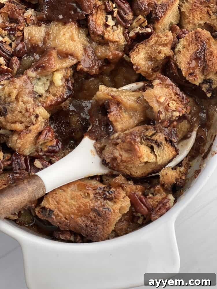 a spoon lifting a scoop of panettone bread pudding with pecan pie filling from a baking dish.