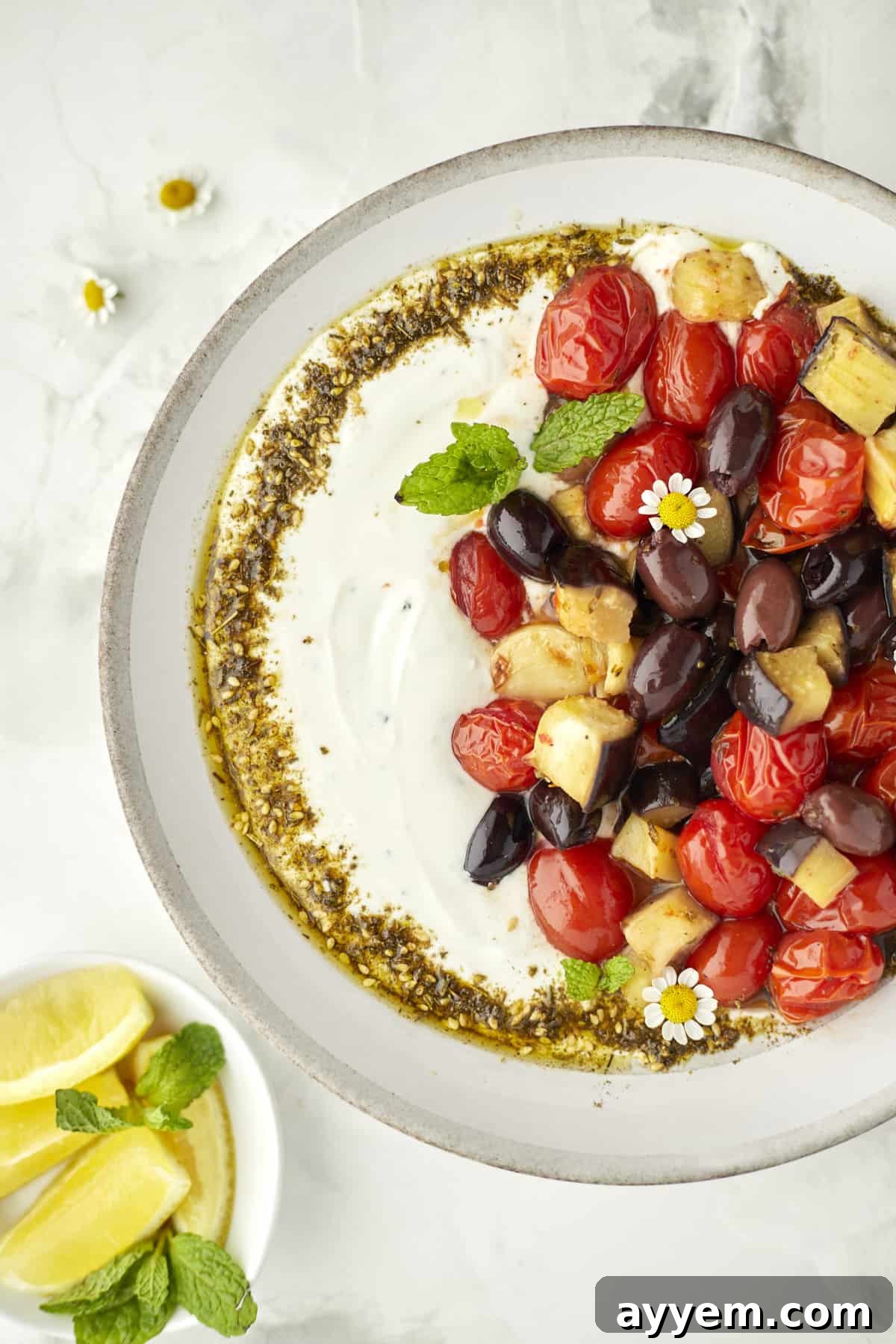 Roasted Eggplant, tomatoes, and olives plated with creamy yogurt dip