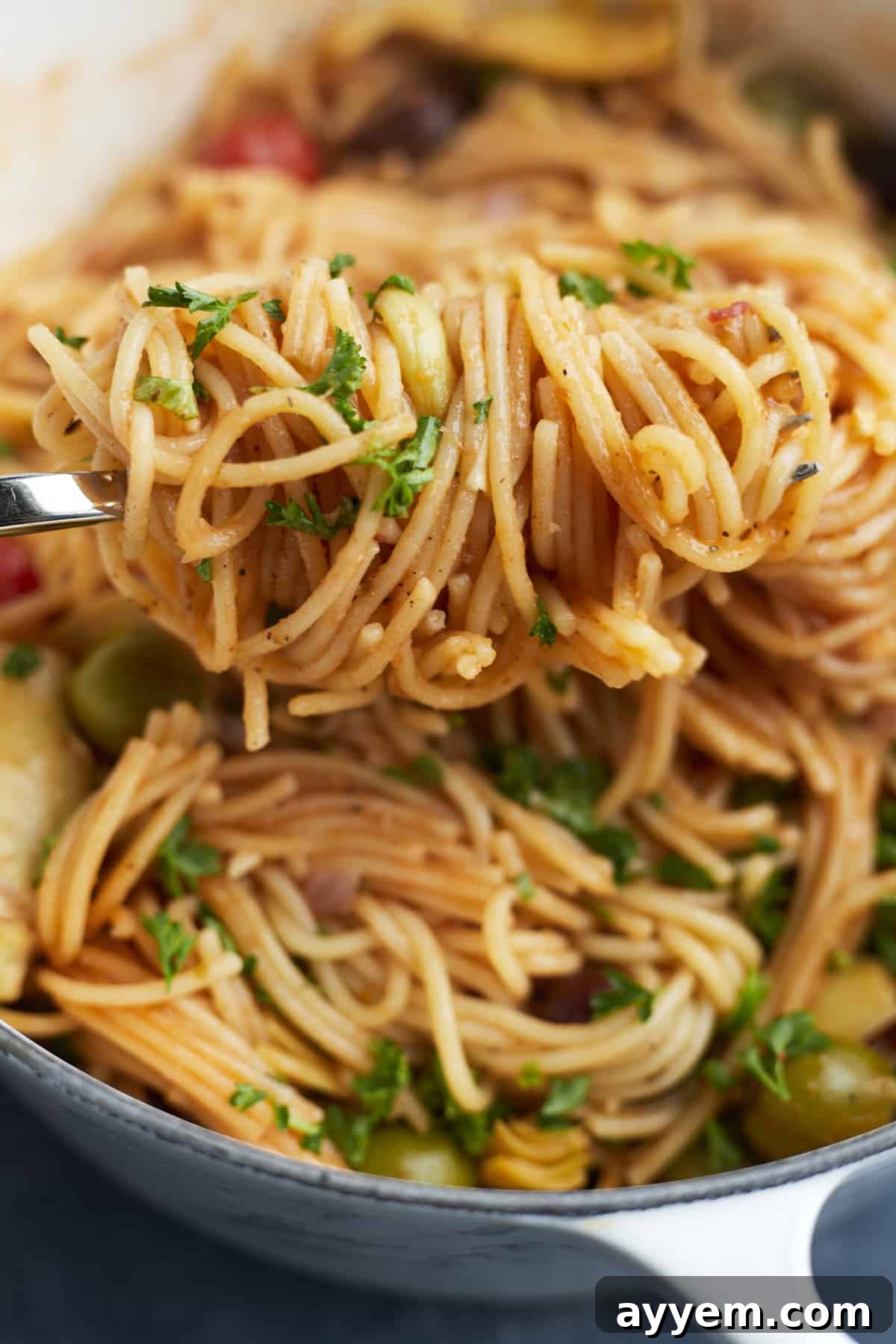 A close-up of One Pot Greek Spaghetti twirled elegantly on a fork, showcasing the rich sauce and embedded vegetables.