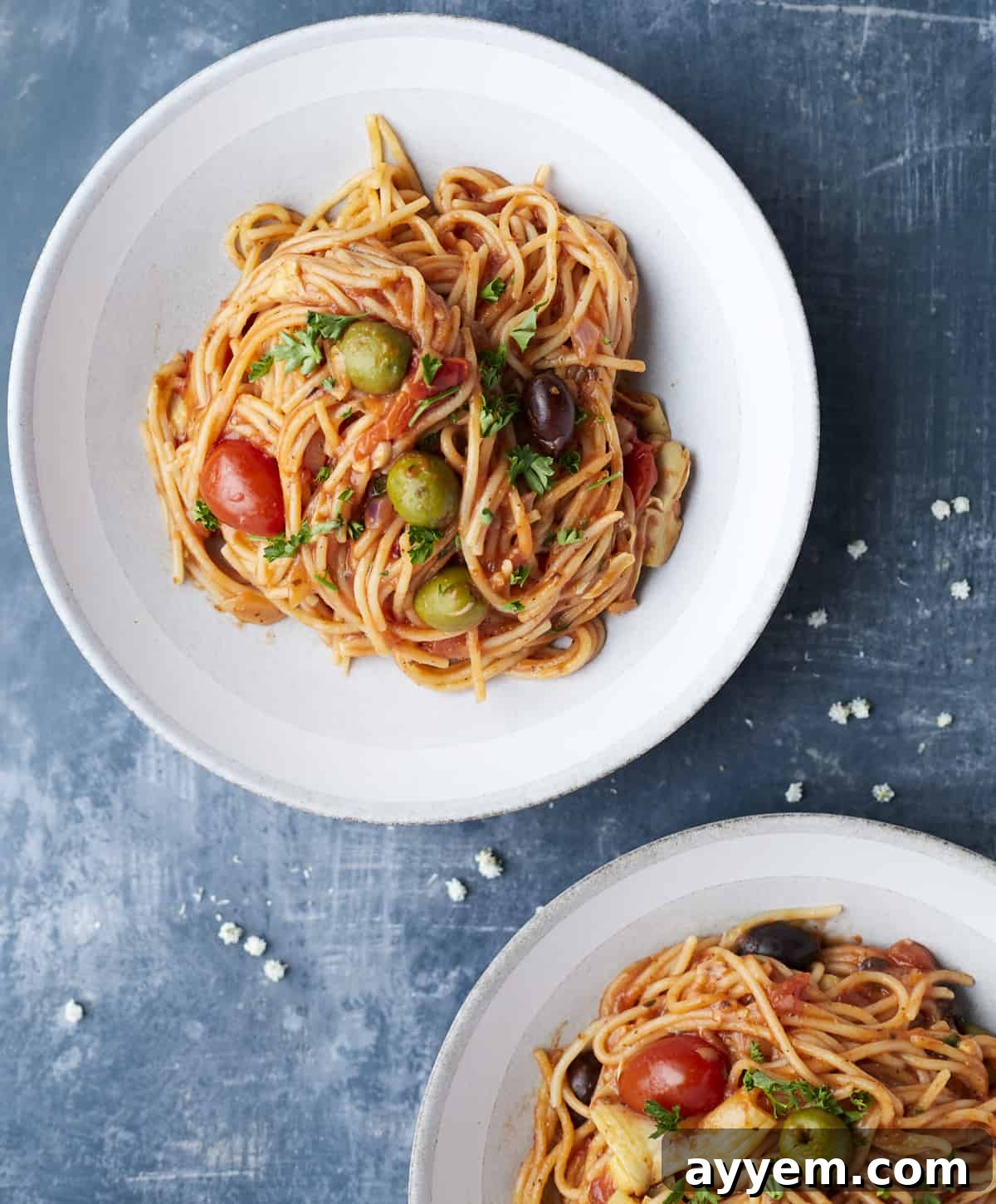 An inviting overhead shot showing two plates of steaming One Pot Greek Spaghetti, beautifully garnished and ready to be served.