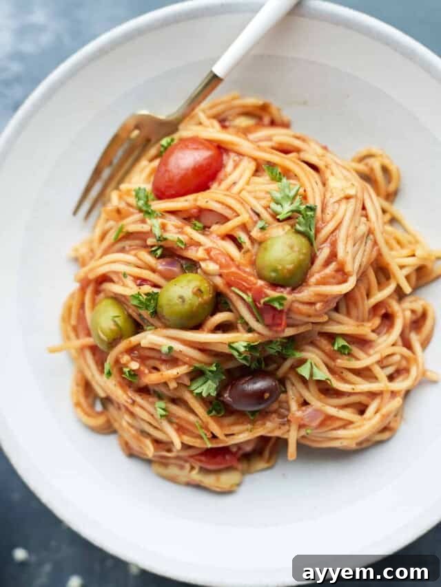 a serving of Greek spaghetti on a white plate with a fork