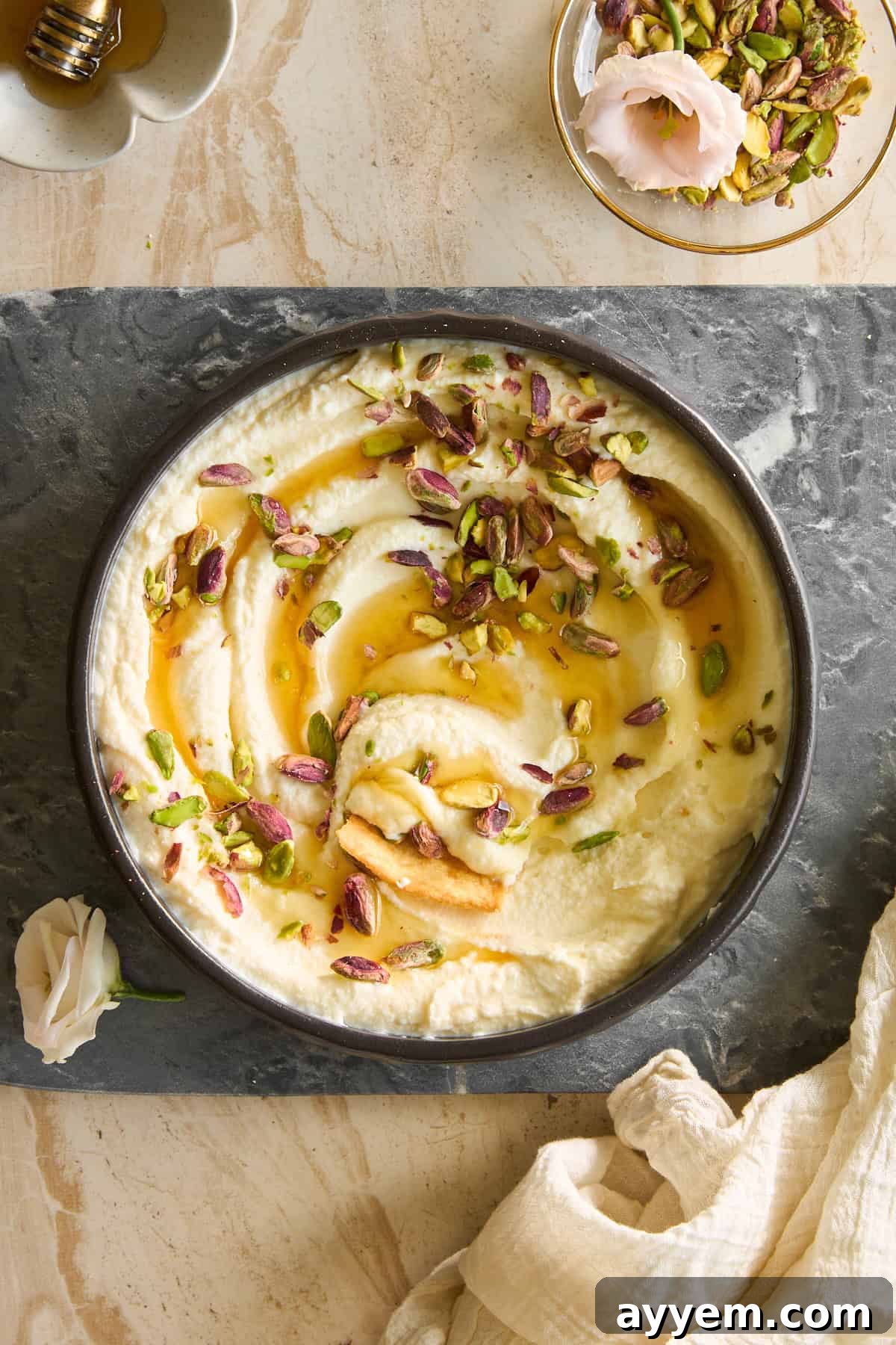 Dreamy Honey Pistachio Ricotta 4 A serving platter filled with creamy whipped ricotta, topped with roasted pistachios and drizzled with golden honey, surrounded by fresh bread and fruit.