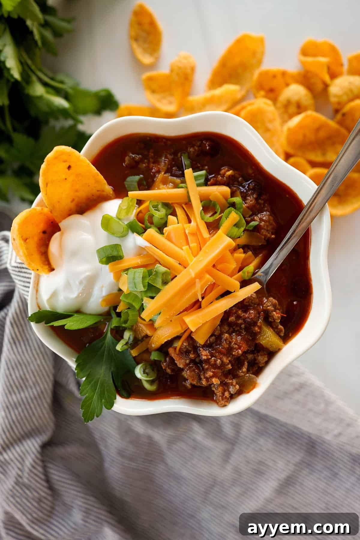 bowl of chili with sour cream, cheese, green onions and corn chips