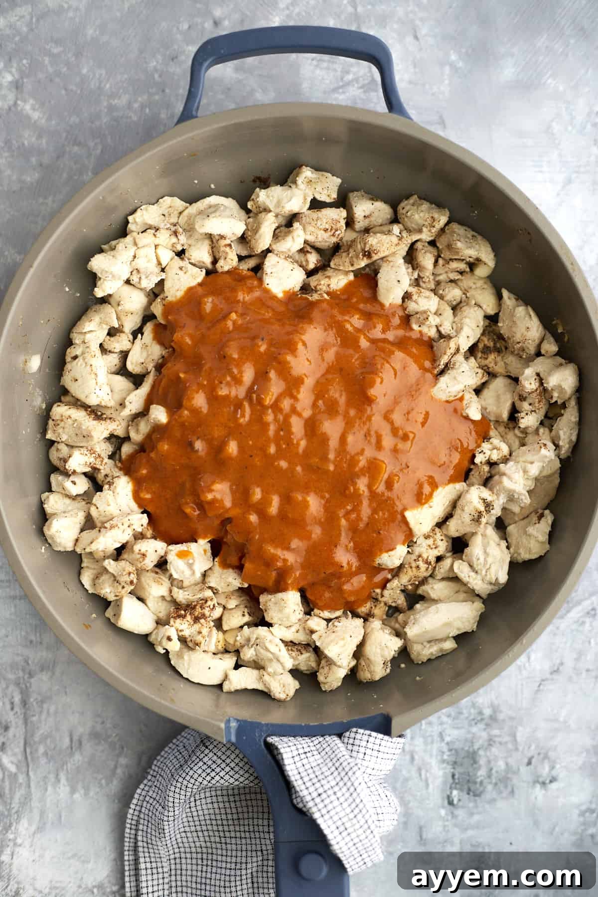 Chicken pieces in a skillet coated with rich Madras curry sauce.