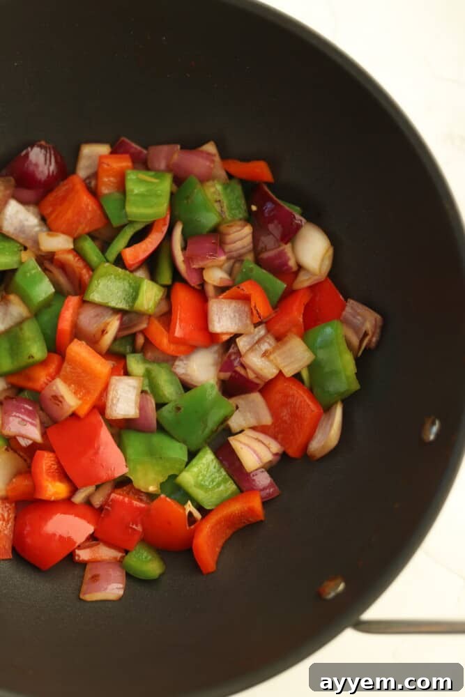 chopped red and green peppers in a wok with red onions