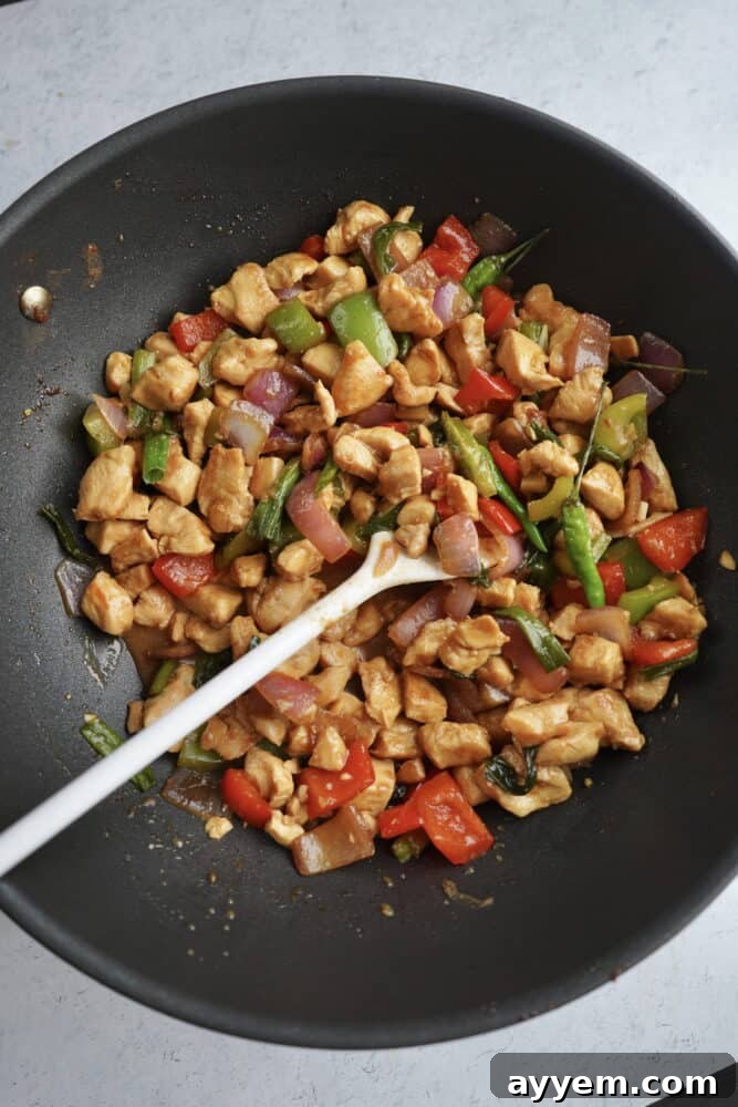 overhead image of a wok with kung pao chicken being stirred with a spoon
