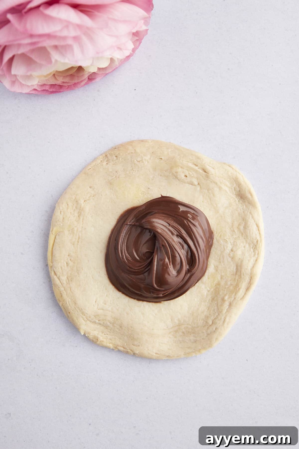 Raw biscuit dough flattened into a circle with a dollop of Nutella in the center.