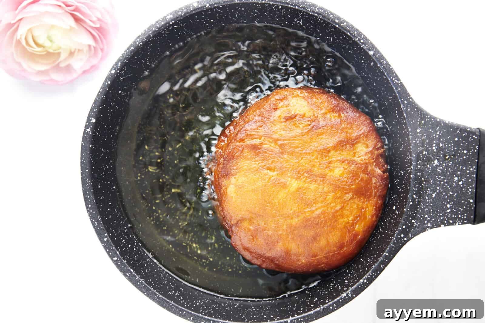 A Nutella stuffed doughscuit frying in oil.