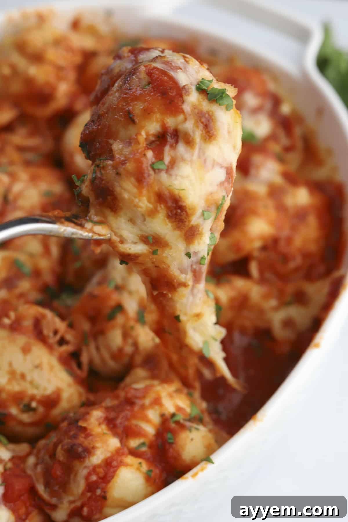 A single golden-brown cheesy garlic knot, perfectly baked and served on a fork, ready to be enjoyed.