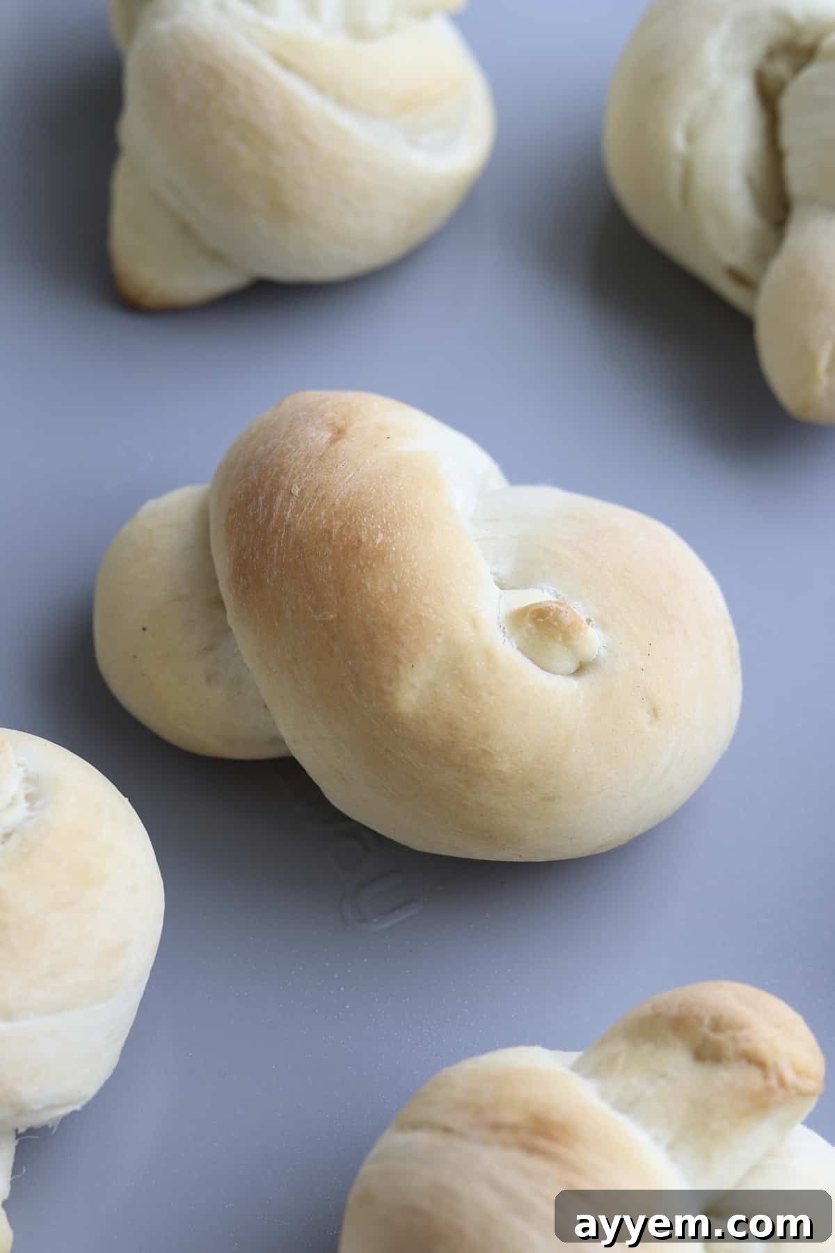 A batch of golden-brown baked garlic knots, fresh out of the oven, before the cheesy topping is added.