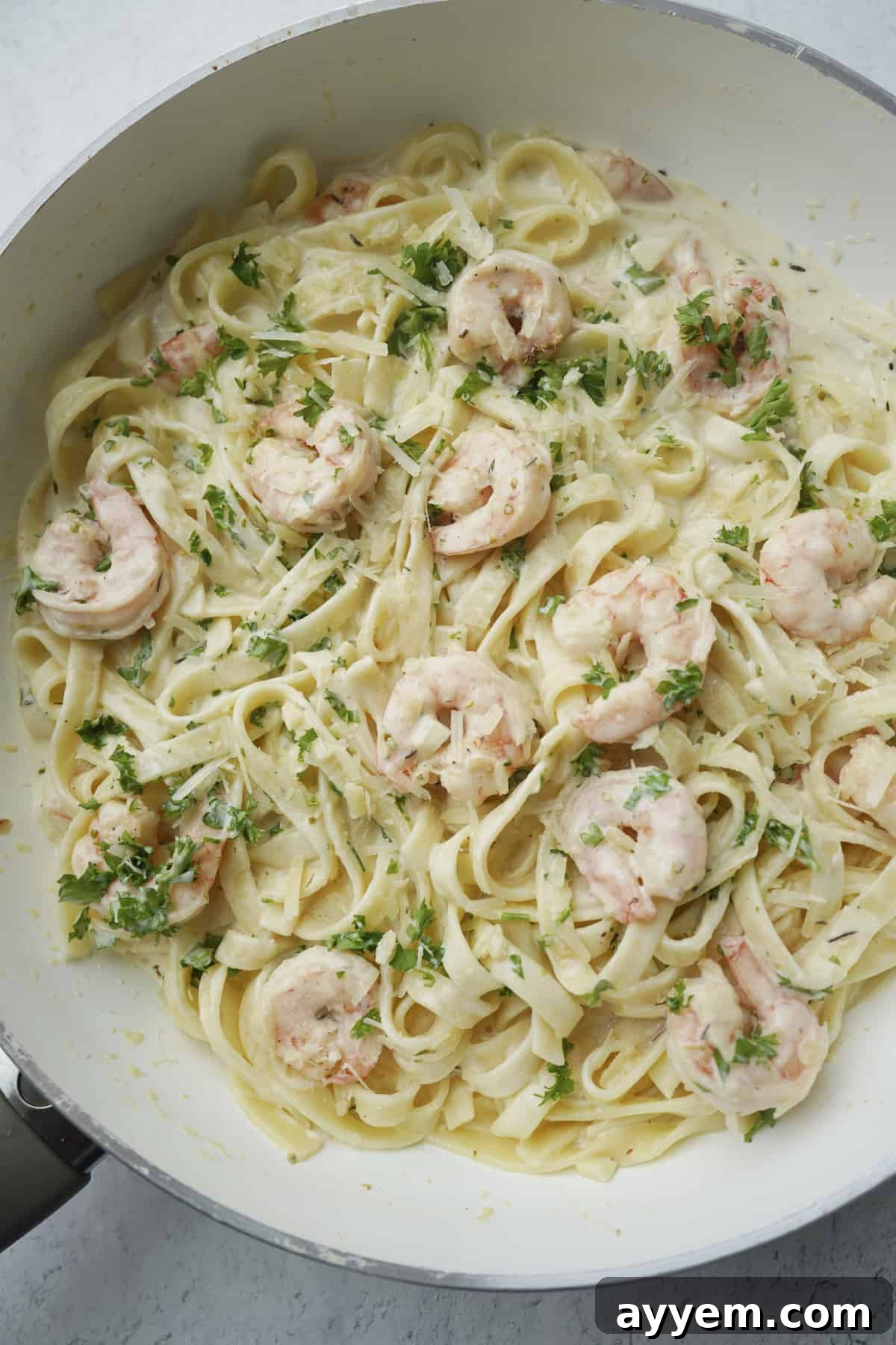 overhead of shrimp linguine with fresh parsley in a pan