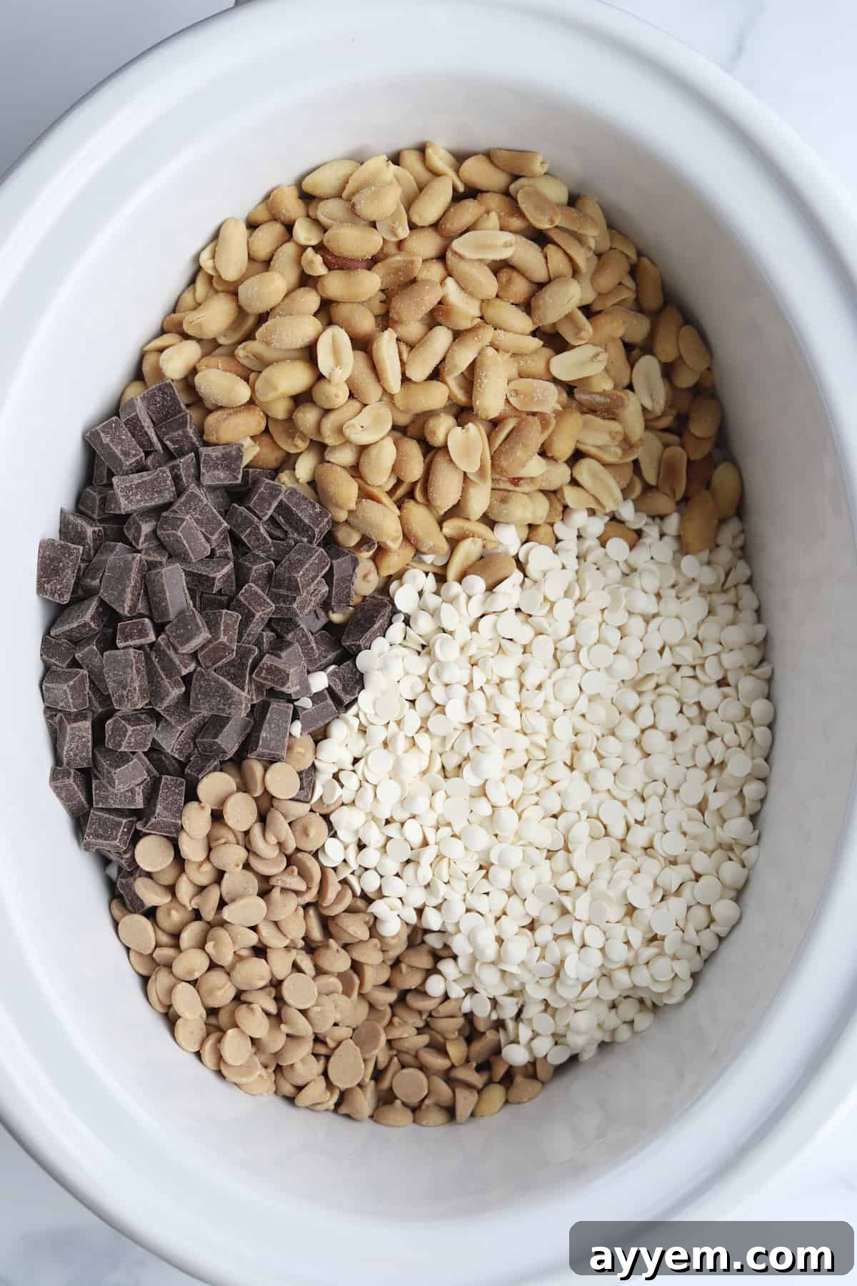 peanuts, white chocolate chips, dark chocolate chunks, and peanut butter chips in a slow cooker