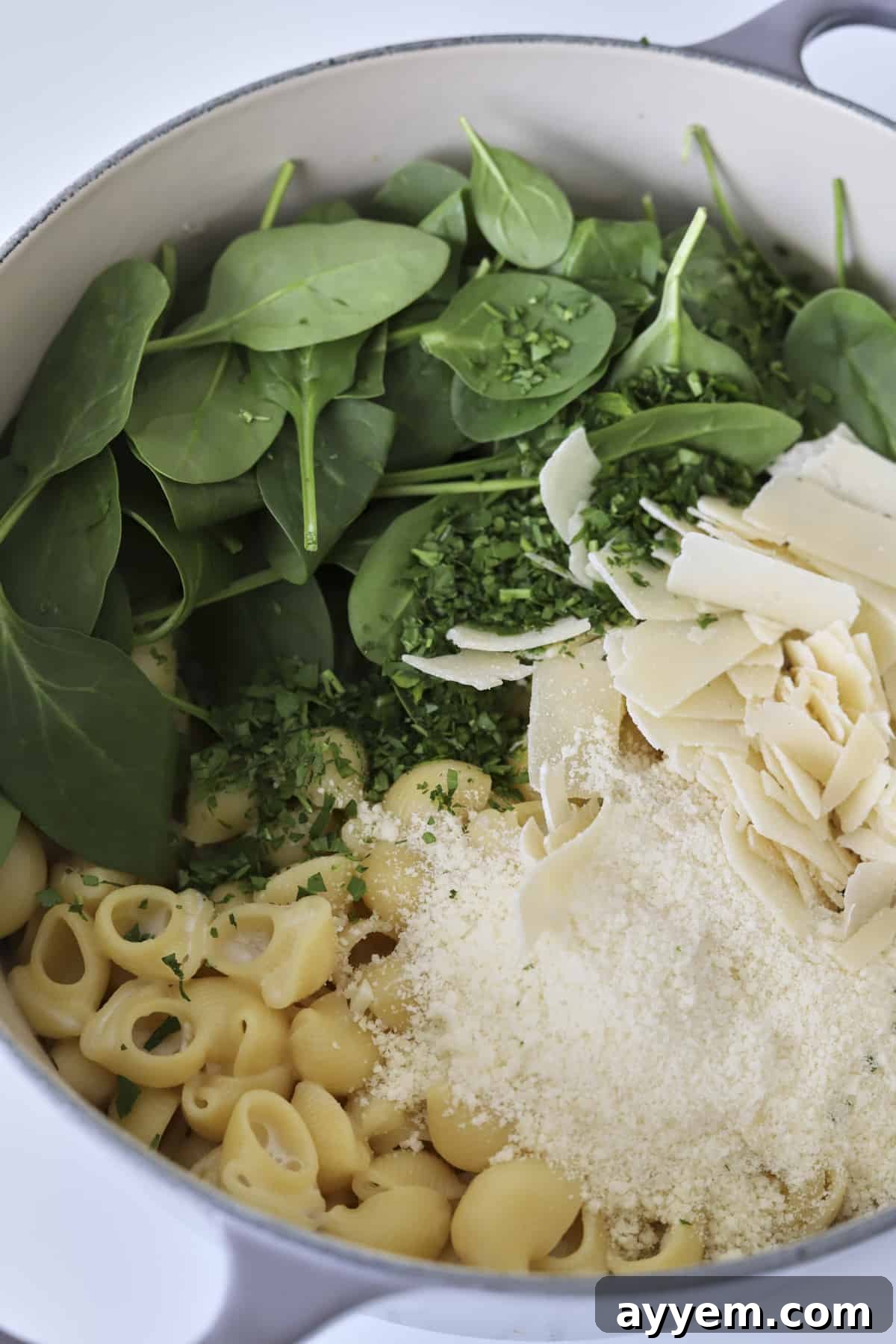 Overhead view of a finished one-pot lemon garlic pasta with spinach and generous parmesan cheese sprinkles.