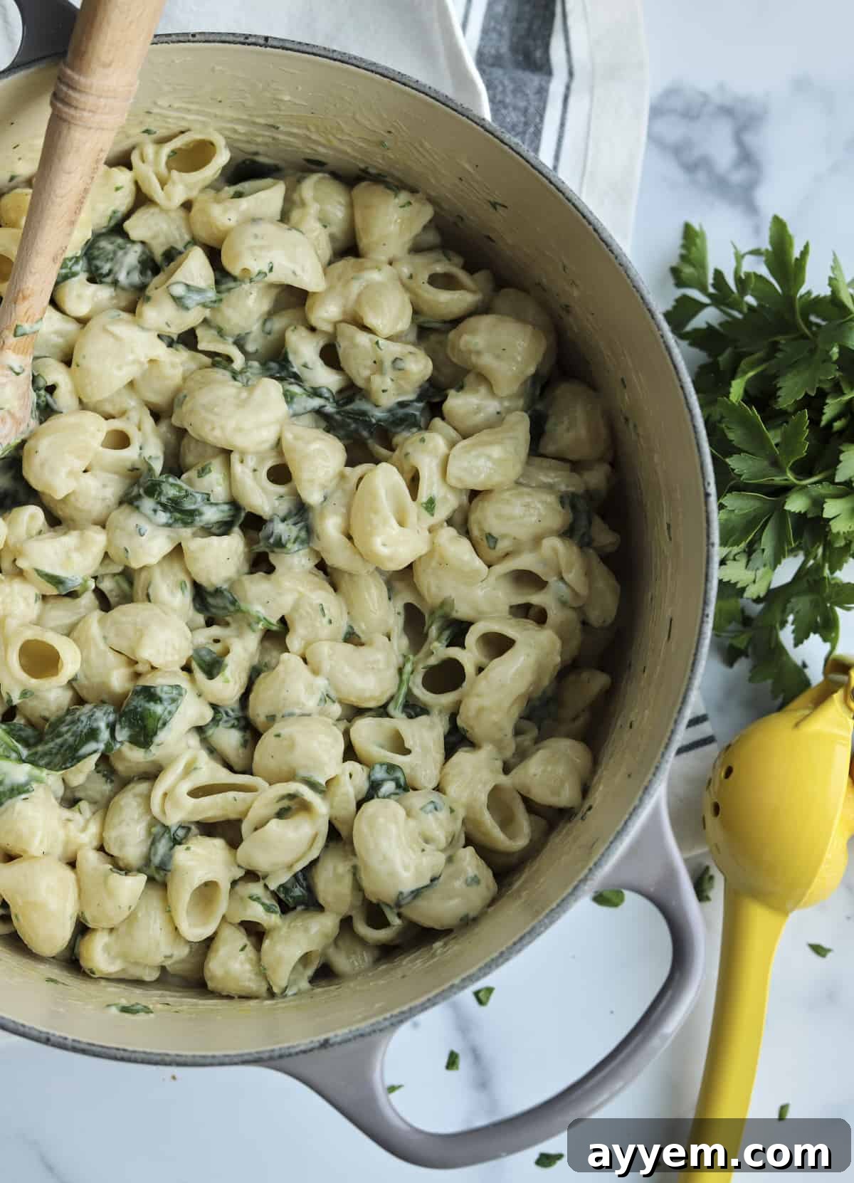 Overhead image of a pot of one-pot lemon garlic pasta with a wooden spoon sticking out, ready to serve.