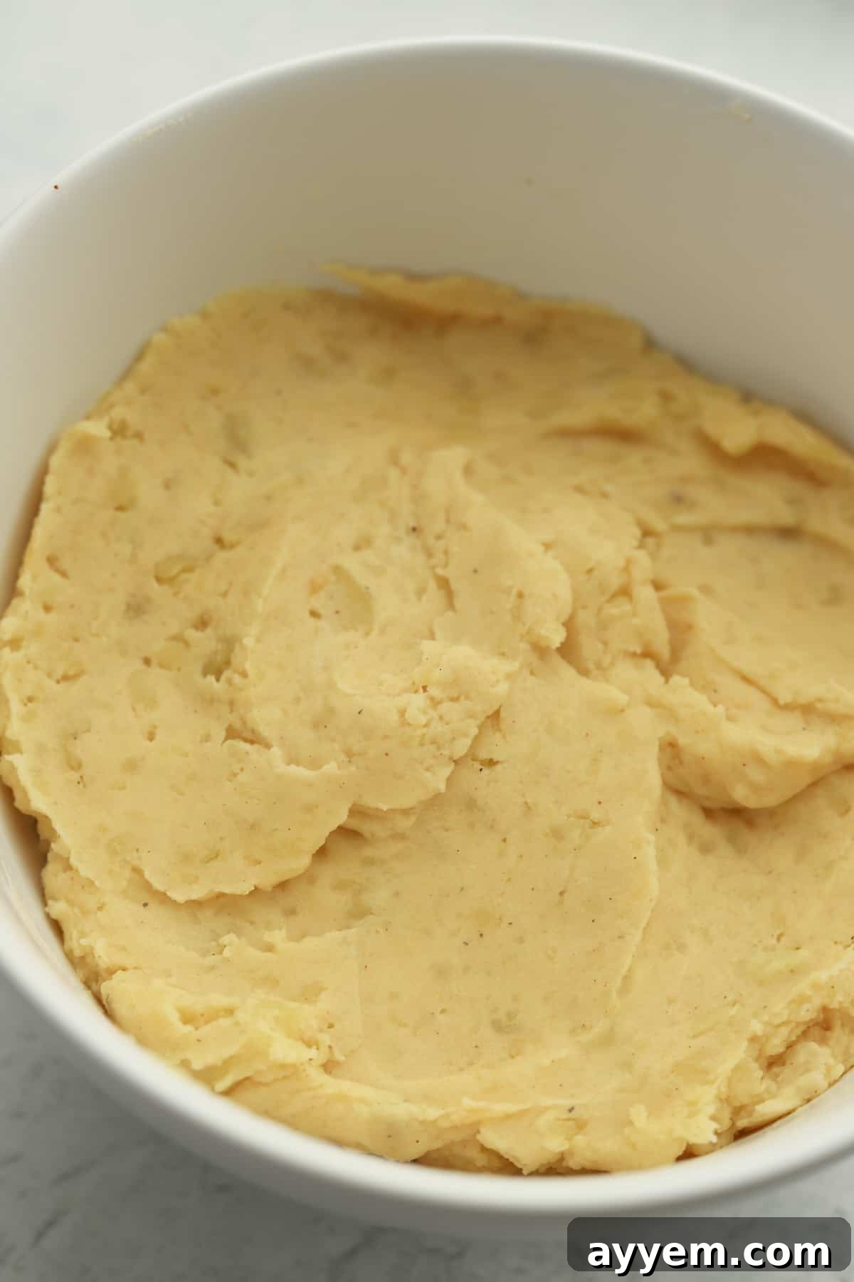 Boiled and drained potato slices in a mixing bowl.