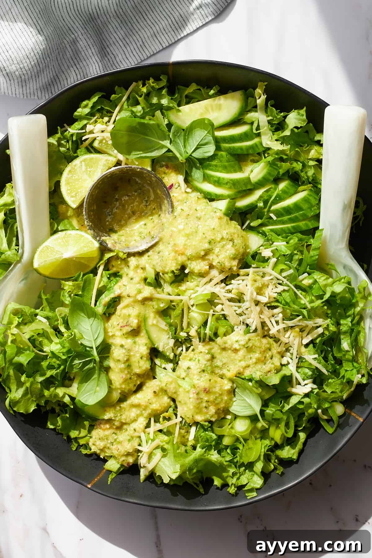 A bowl of green goddess salad with green goddess dressing on top. 
