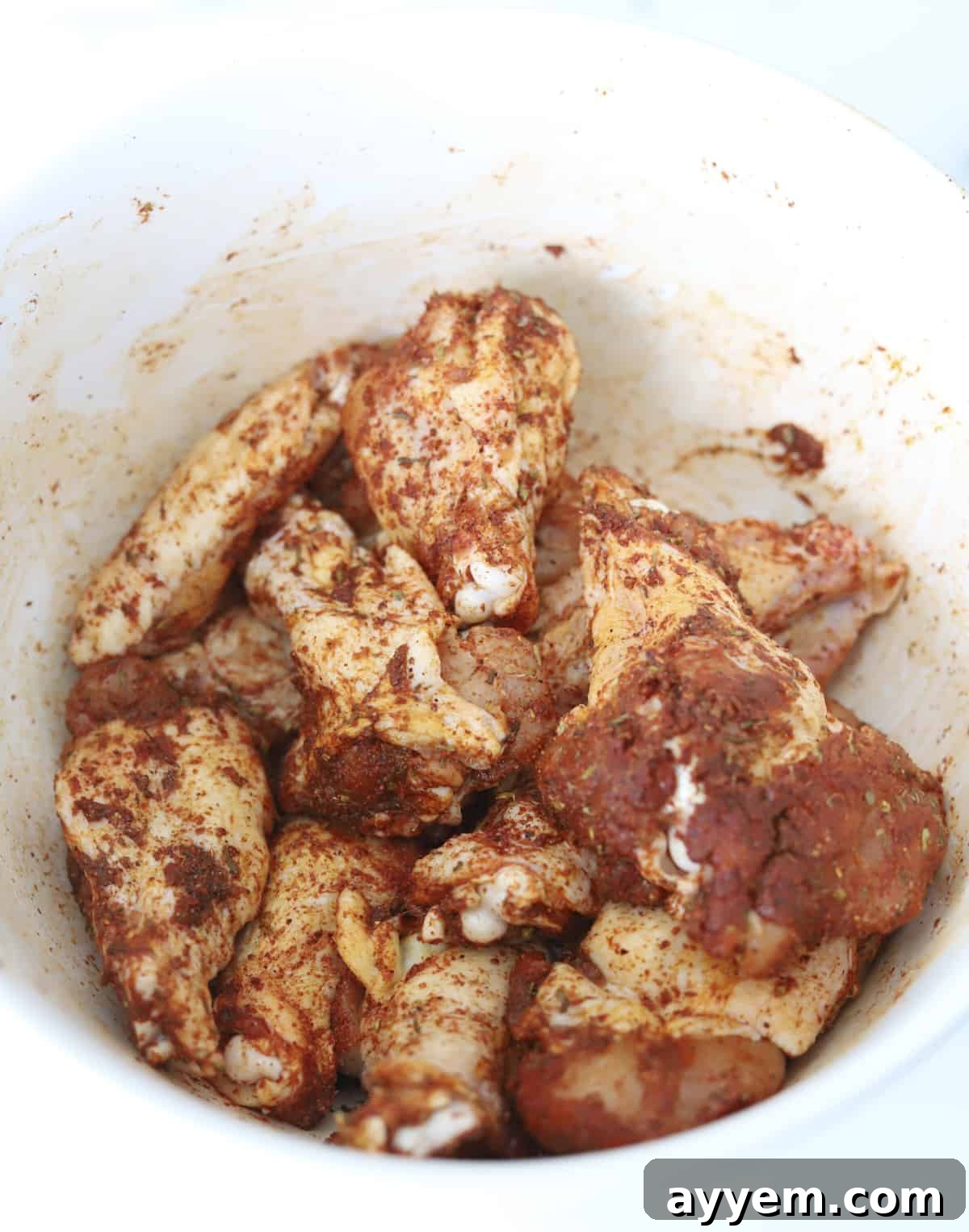 raw chicken wings in a bowl coated with spices