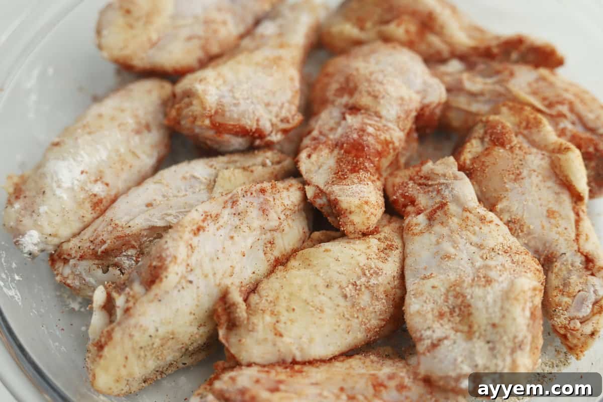 Close-up of chicken wings evenly coated in seasoning and cornstarch in a bowl.
