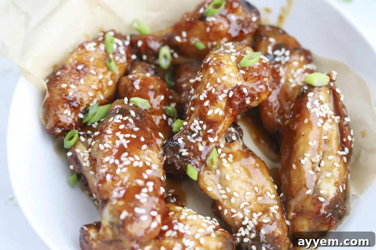 A beautifully arranged bowl of air fryer honey garlic chicken wings, garnished with bright green onions and sesame seeds, ready for serving.