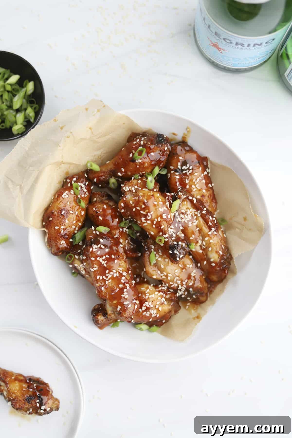 A bowl of air fryer honey garlic chicken wings topped with sesame seeds.