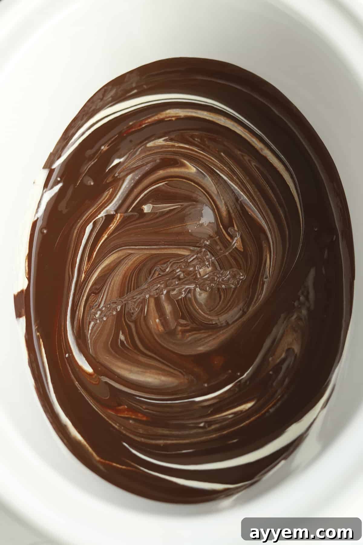 Melted chocolate mixture being stirred in a slow cooker