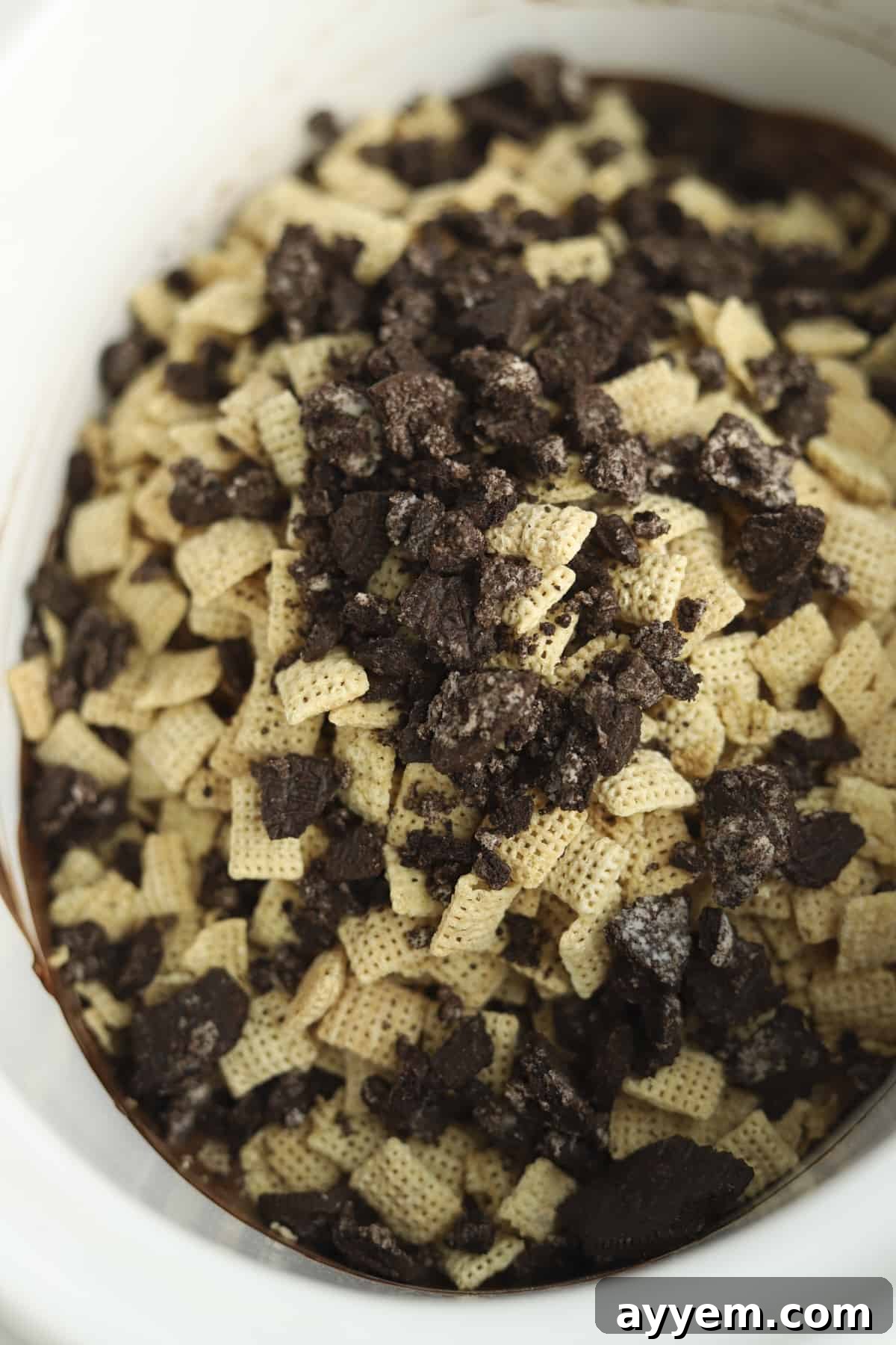 Rice cereal and crushed cookies added to melted chocolate in a slow cooker