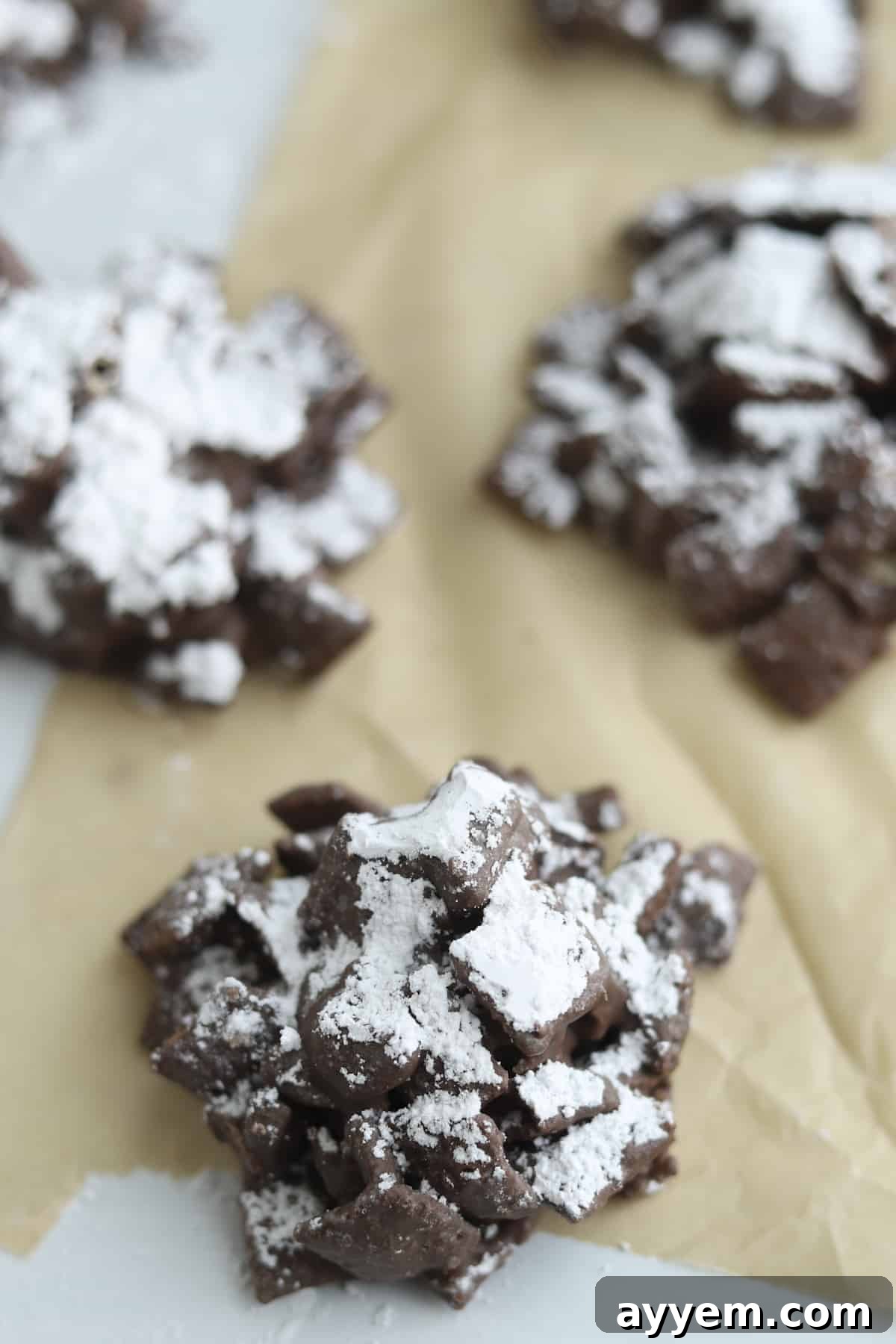 Finished puppy chow clusters coated in powdered sugar on wax paper