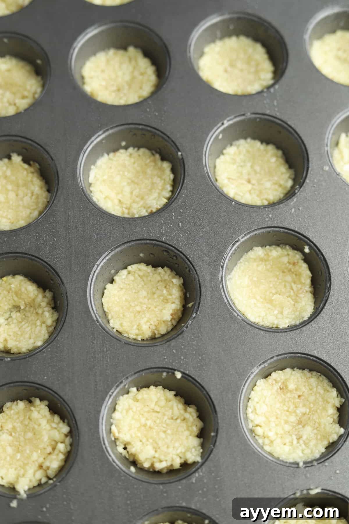 Minced garlic expertly portioned into a mini muffin tin and ready for freezing, a practical way to store garlic for easy, pre-measured use in cooking.