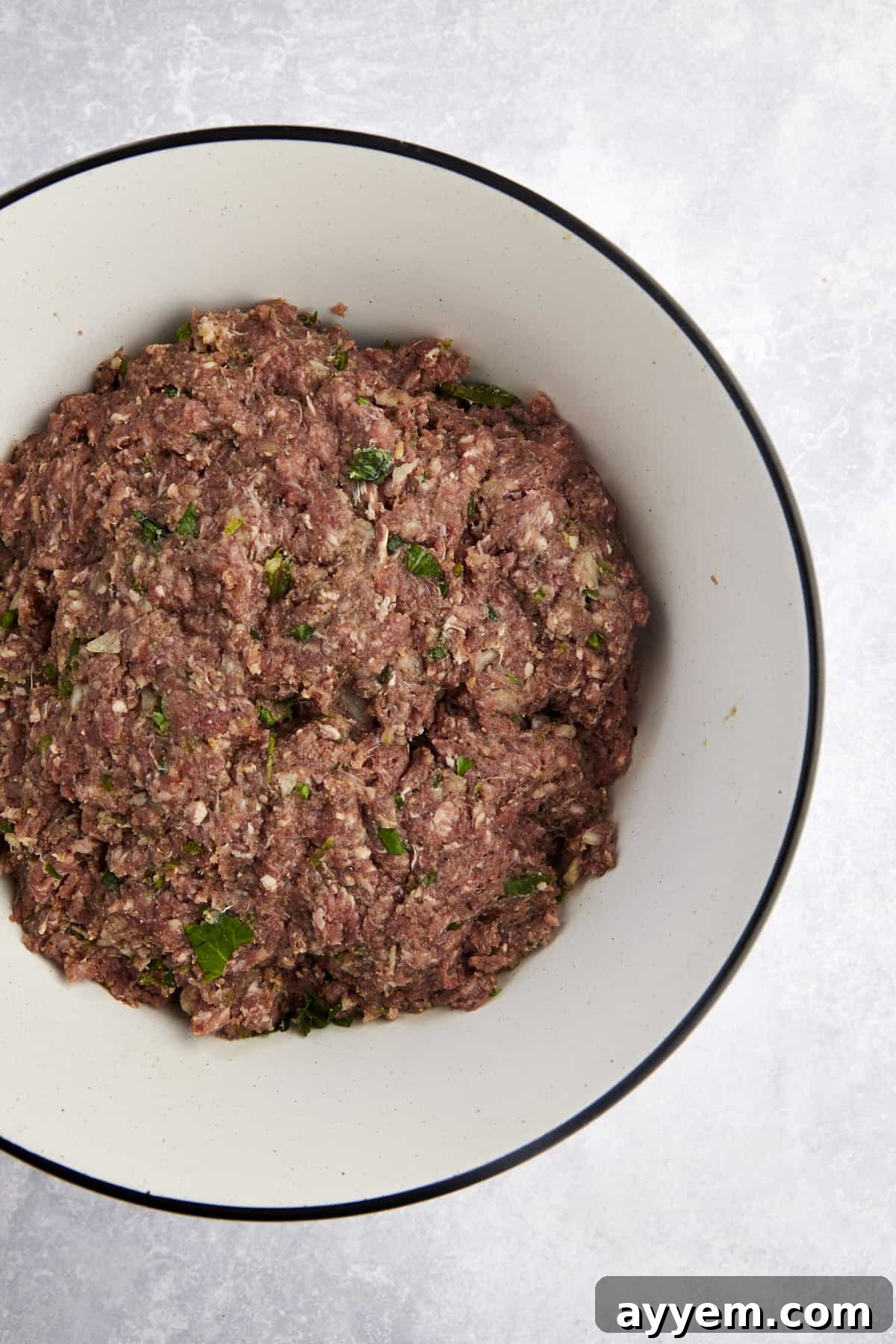 A bowl of raw beef kofta mixture, showcasing the blend of ground beef, herbs, and spices before shaping.