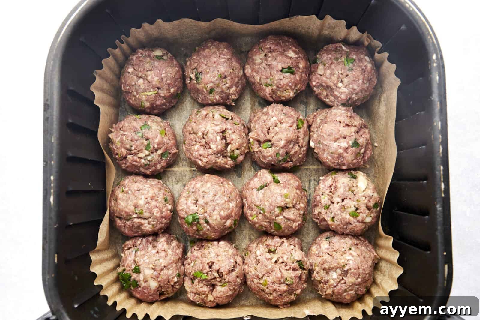 Raw beef kofta meatballs neatly arranged in an air fryer basket, ready for cooking to golden perfection.