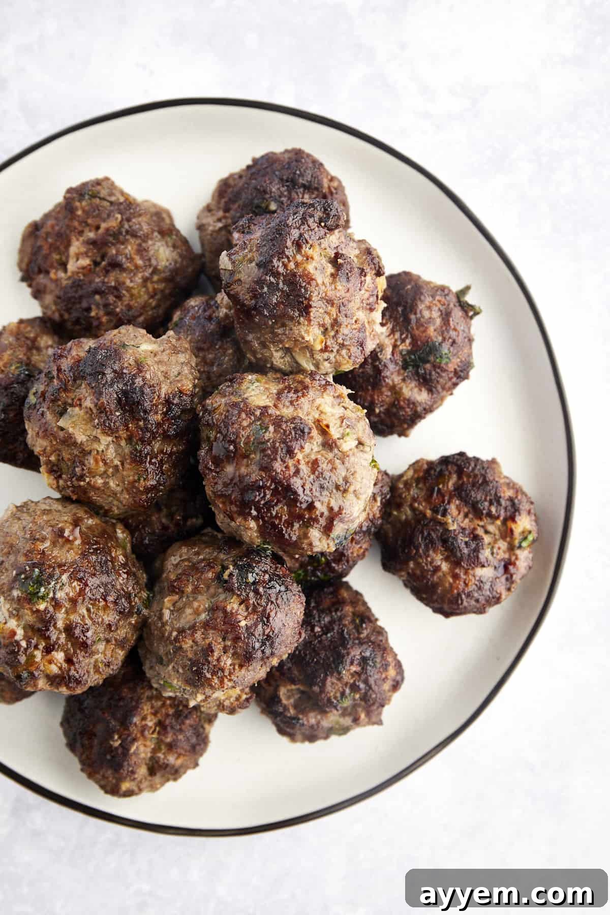 Perfectly cooked beef kofta meatballs garnished with fresh herbs on a pristine white plate, ready to be enjoyed as a delicious meal.